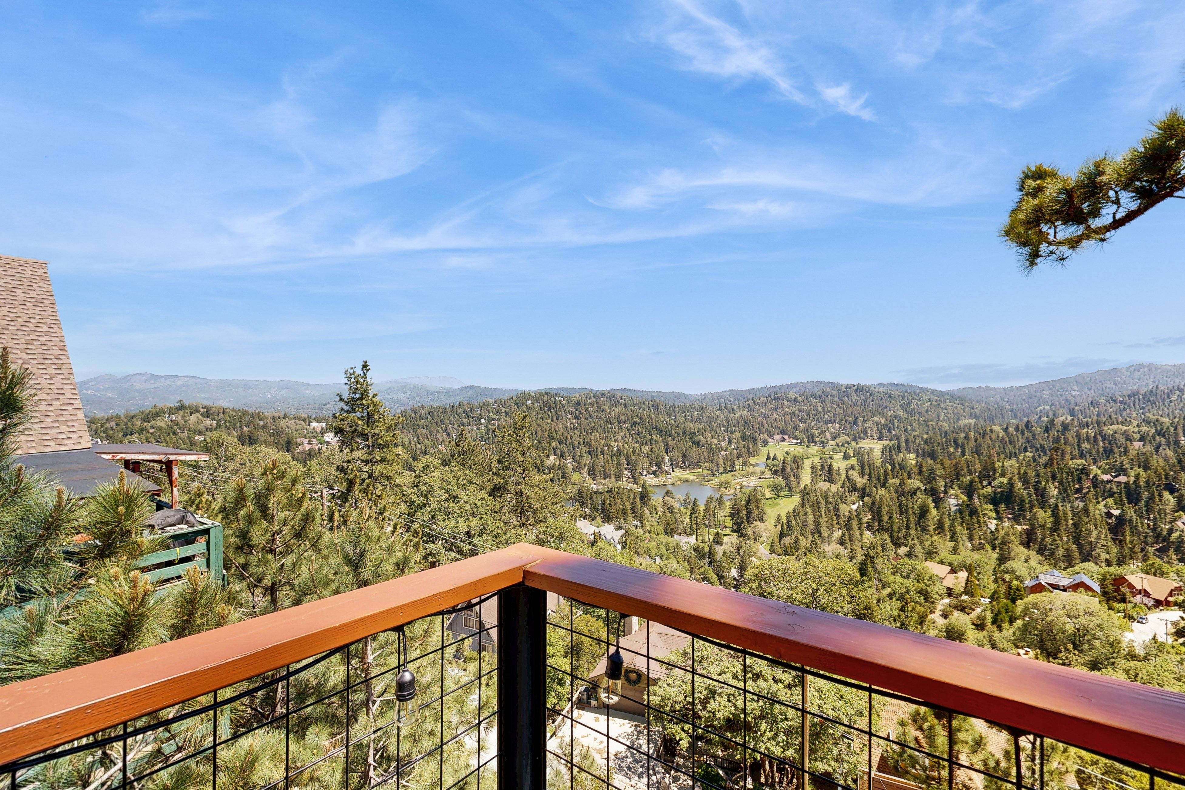 The view from a Lake Arrowhead cabin deck out over pine treetops to the far ranges