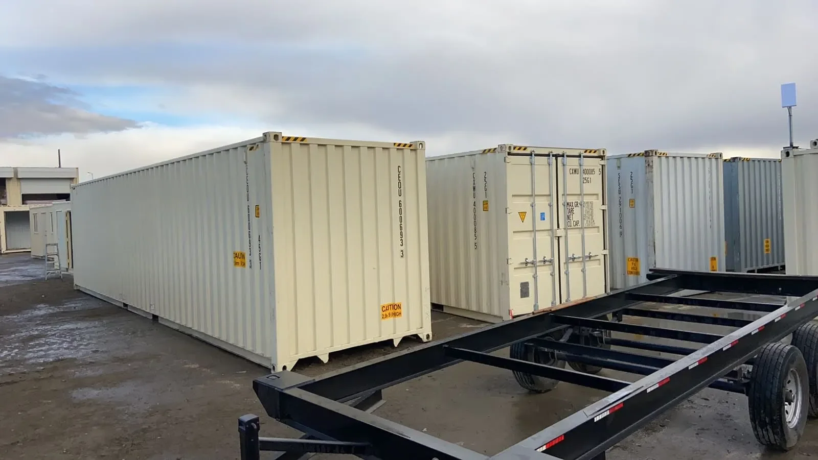 Shipping containers in a storage lot with a container trailer in the foreground