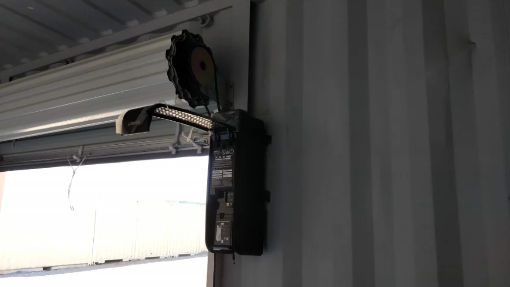 A rolled-up door with the control unit and motor viewed from the inside of a shipping container