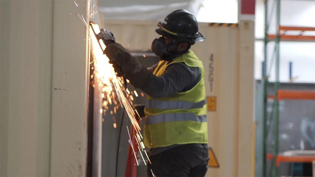 Worker cutting metal panel on shipping container