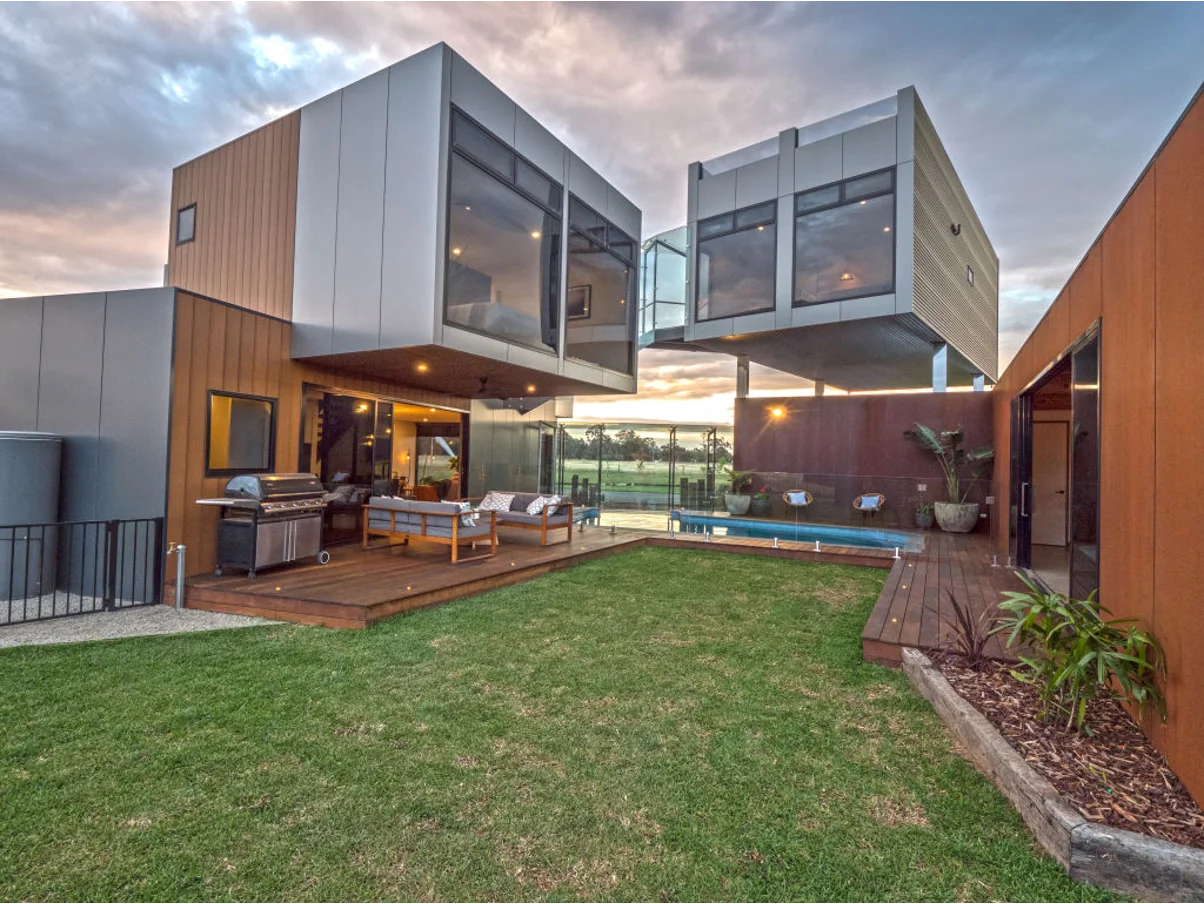 A modern shipping container home exterior with large windows and outdoor space.