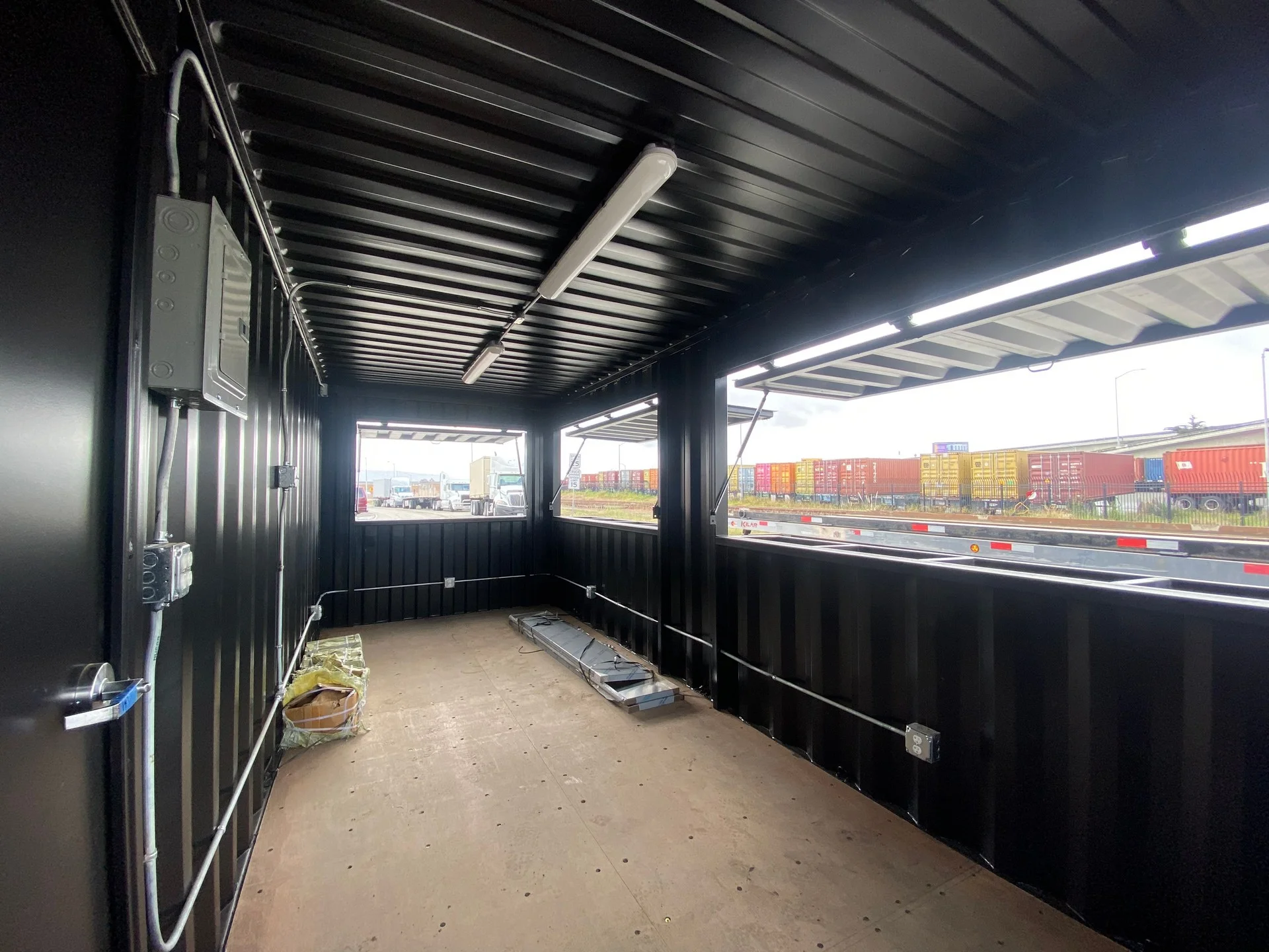 Exterior of an industrial shipping container bar with awnings and service counters