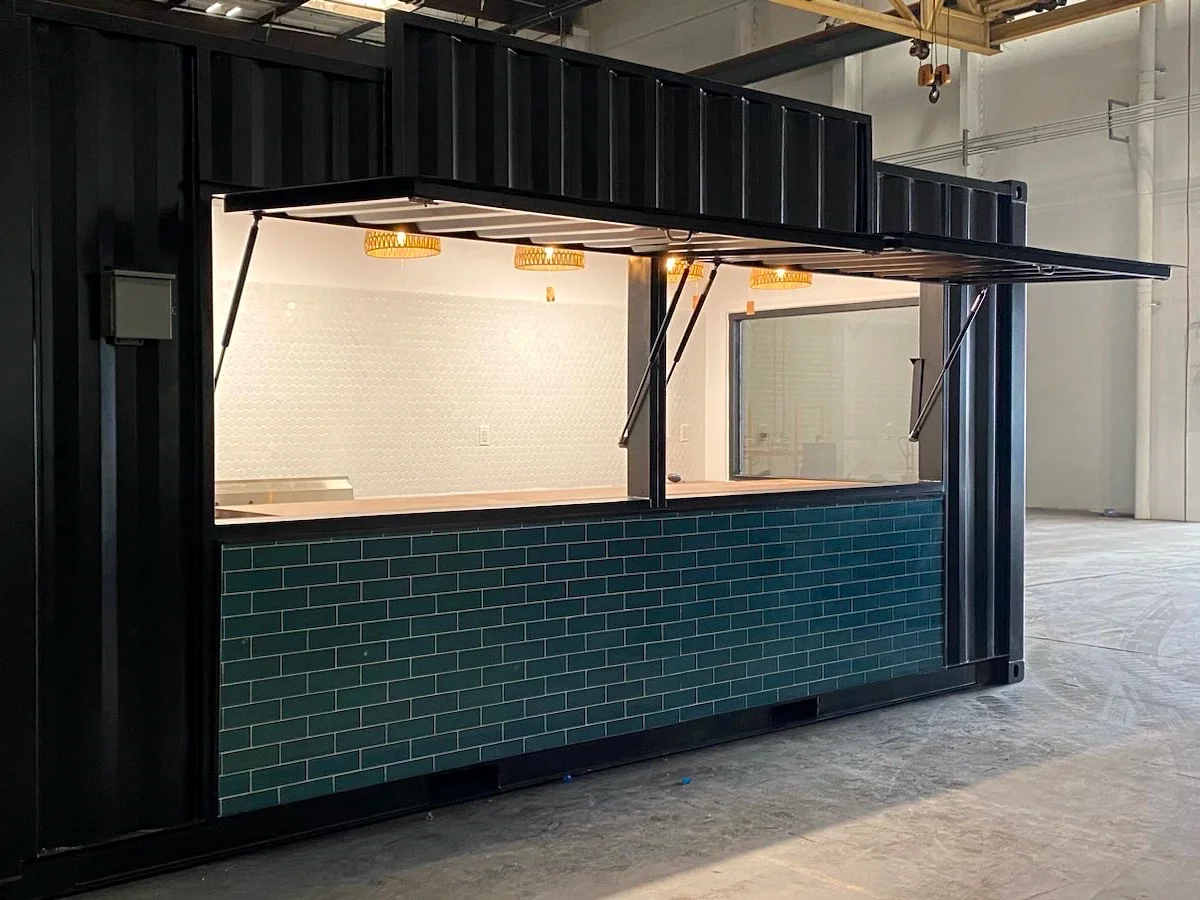 Boba and Brew shipping container cafe with open service awnings, wood counter, teal tile exterior, and finished interior