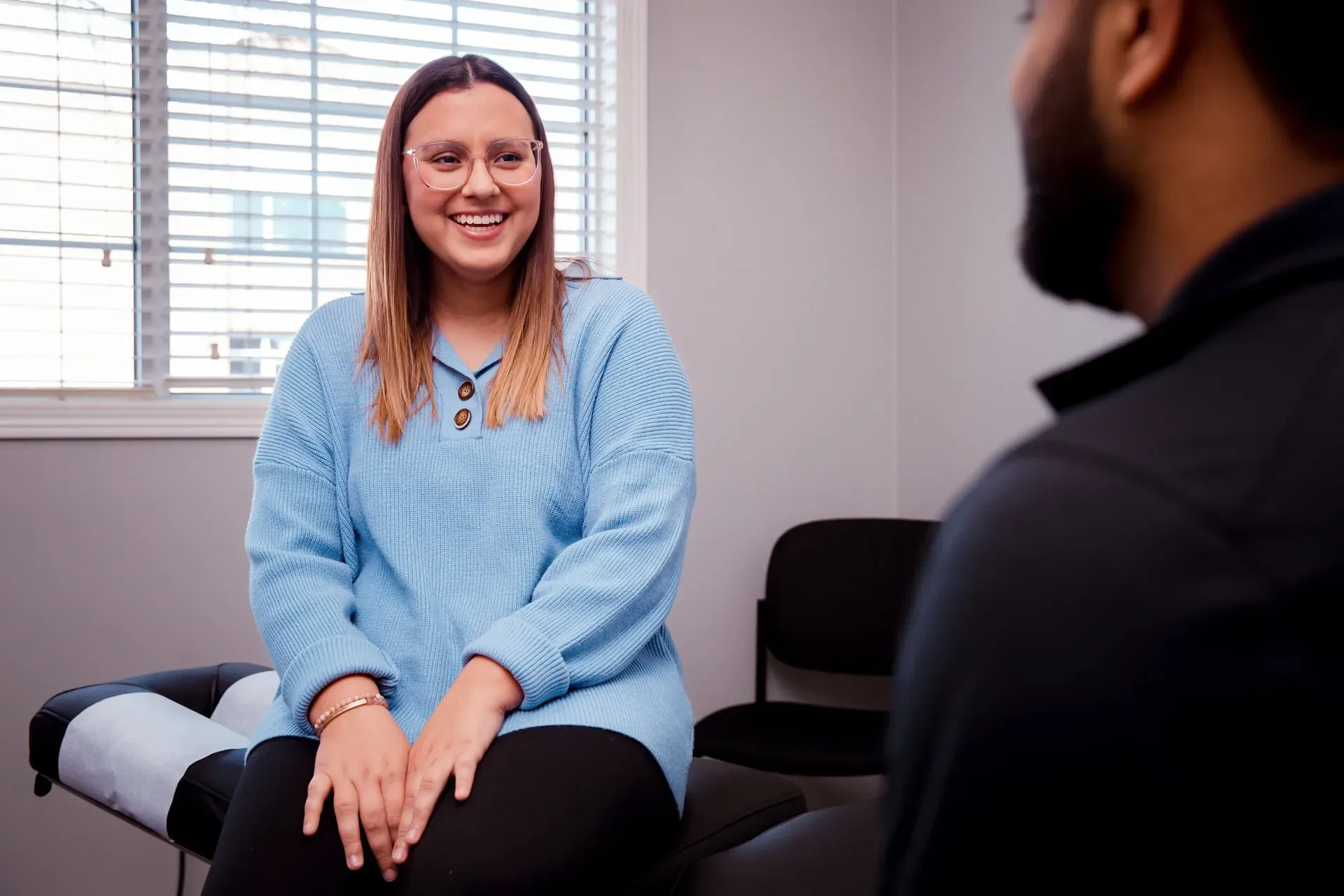 Smiling woman in a blue sweater sitting in a consultation room