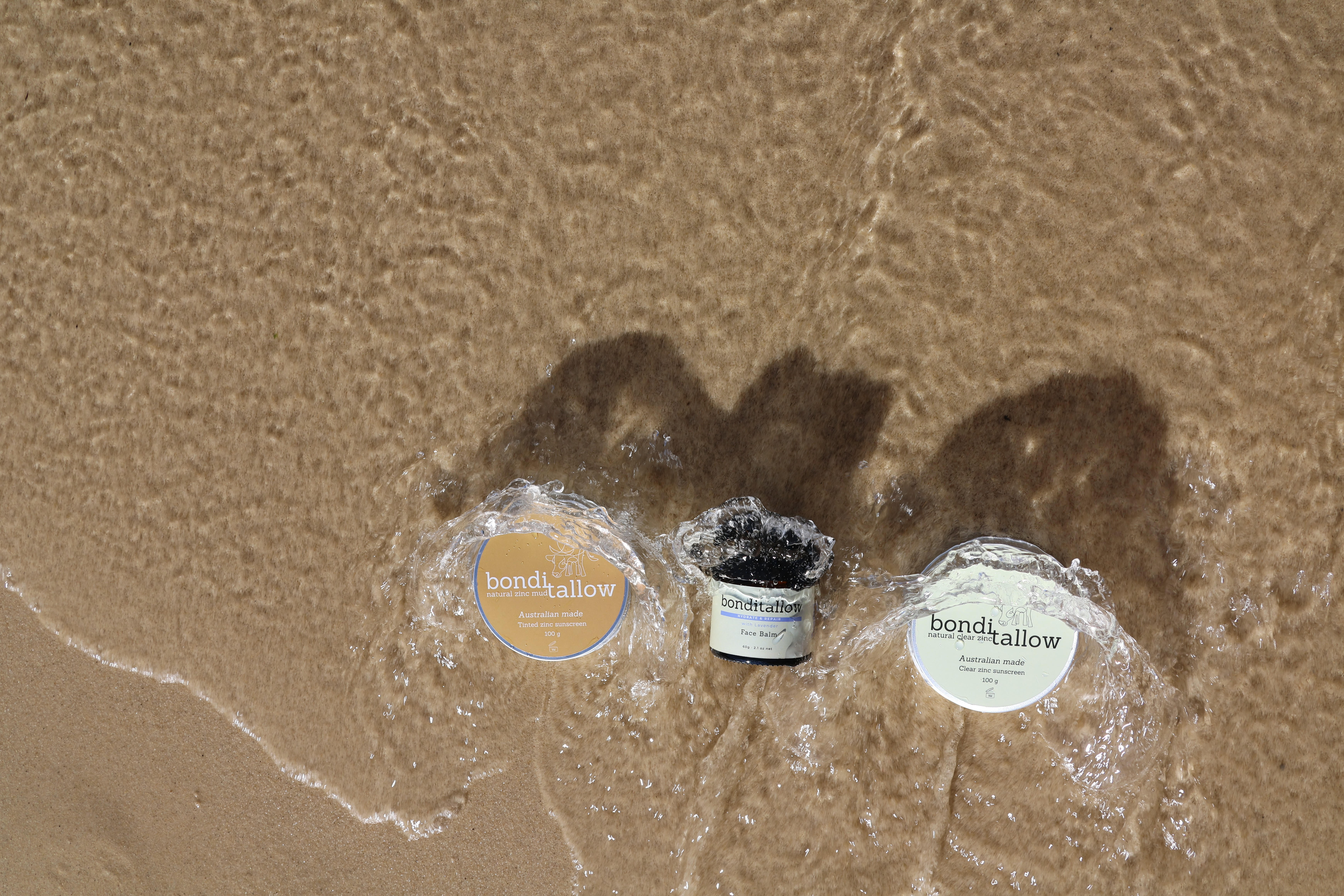 Natural skincare products on wet sand beside ocean waves