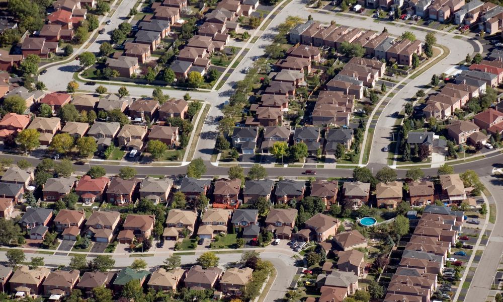An aerial view of a master-planned residential neighborhood with neat rows of family homes, highlighting communities where buyers benefit from long-term new home warranties.