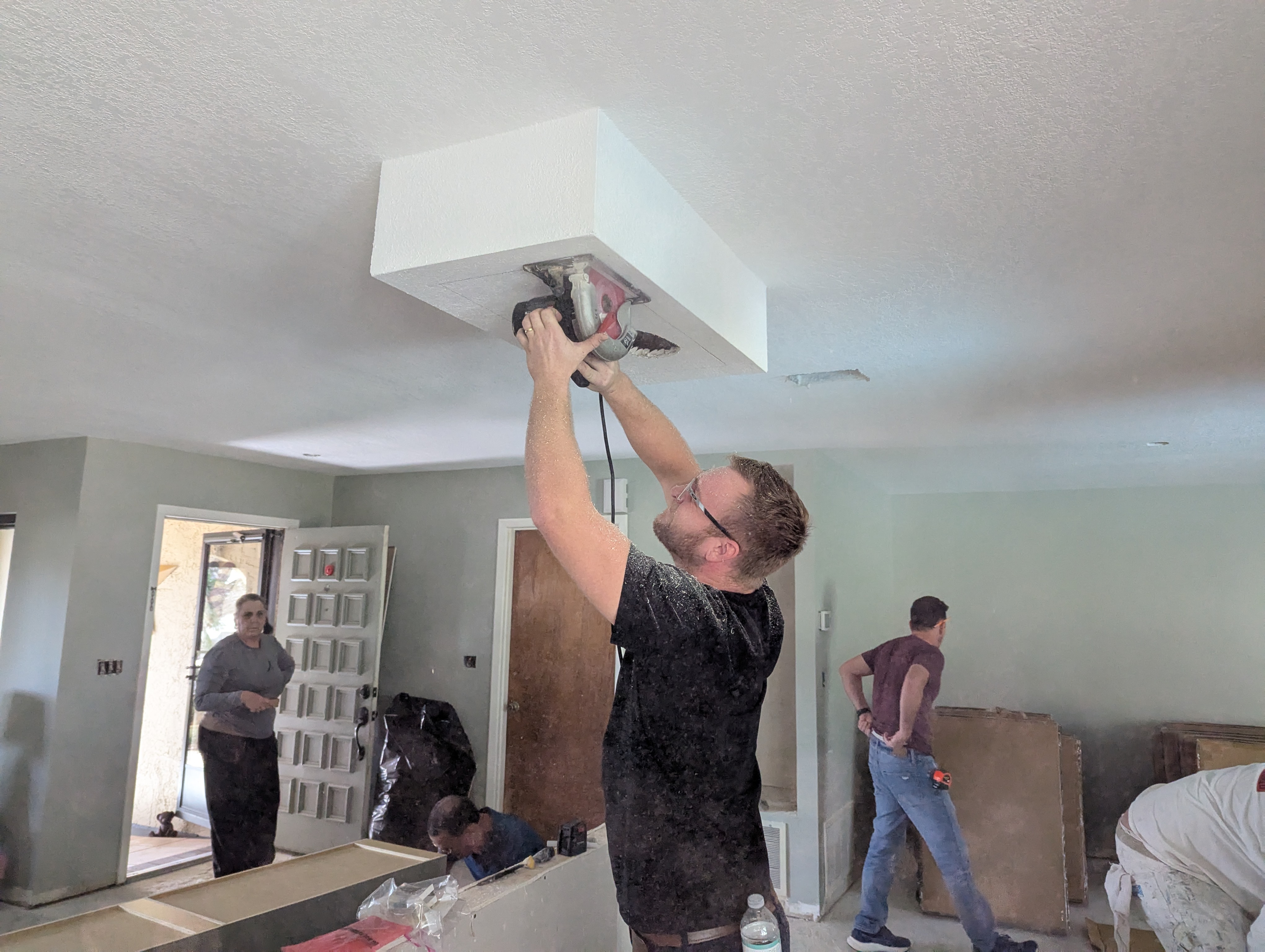 Man using a power tool to open a ceiling access area during home renovation, highlighting potential central AC troubleshooting and repair work.