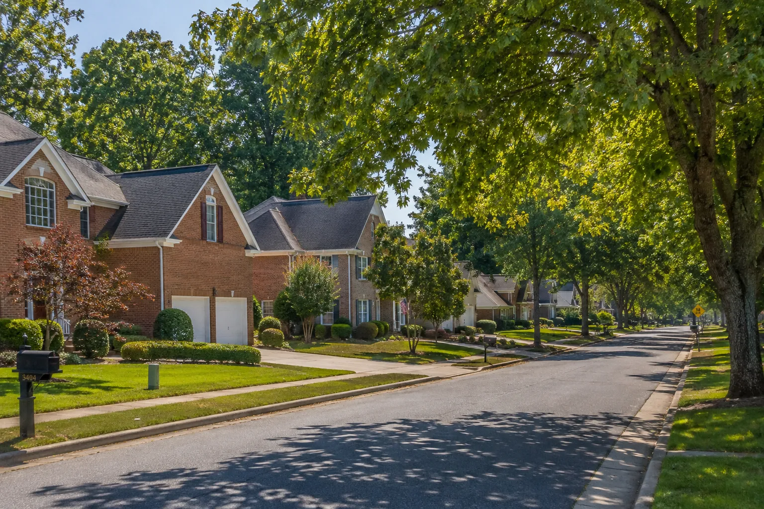A tree-lined residential street in Spotsylvania County with newer construction single-family homes and manicured front lawns.
