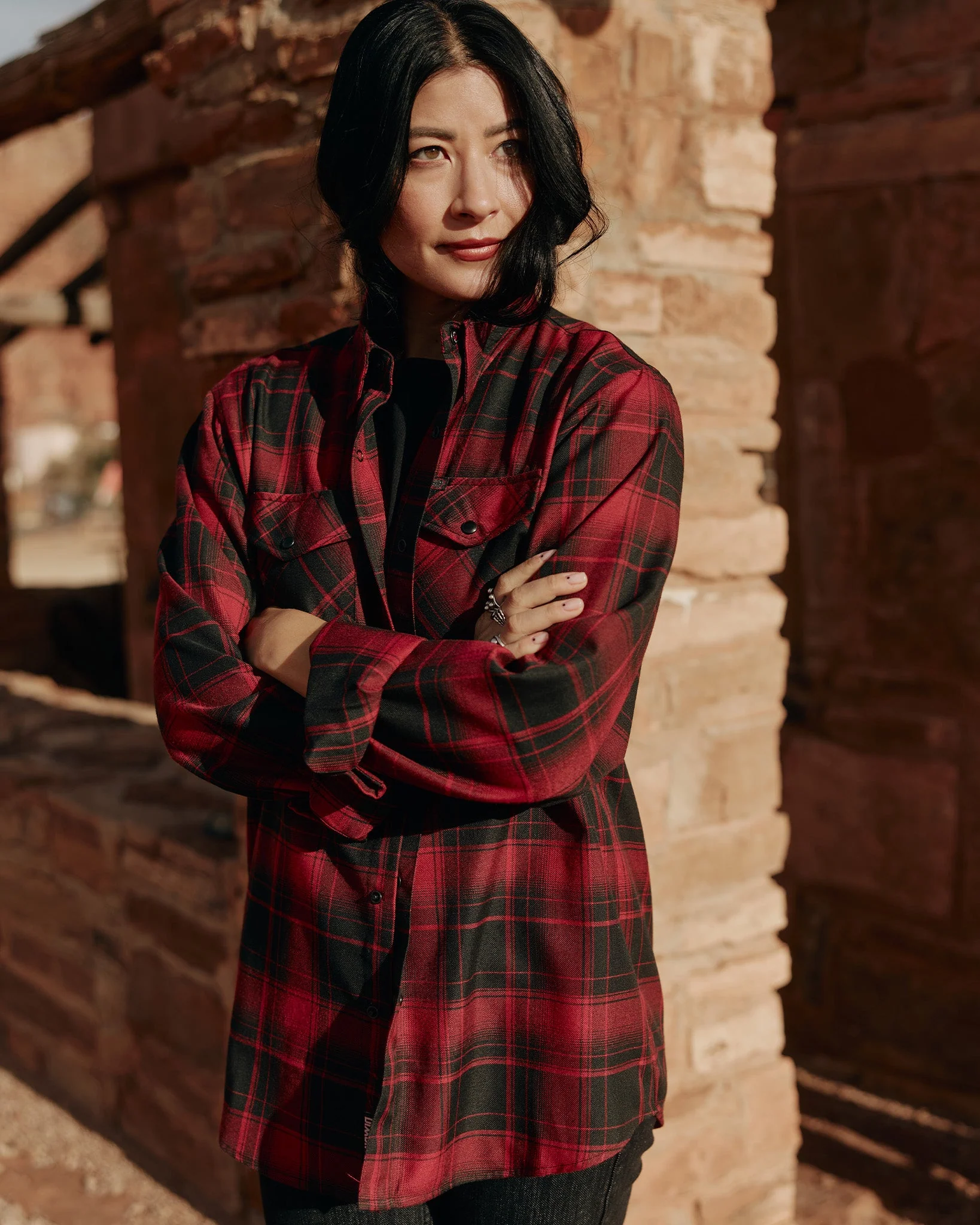 Woman in front of brick structure wearing Women's Indian Motorcycle 125th Anniversary Flannel