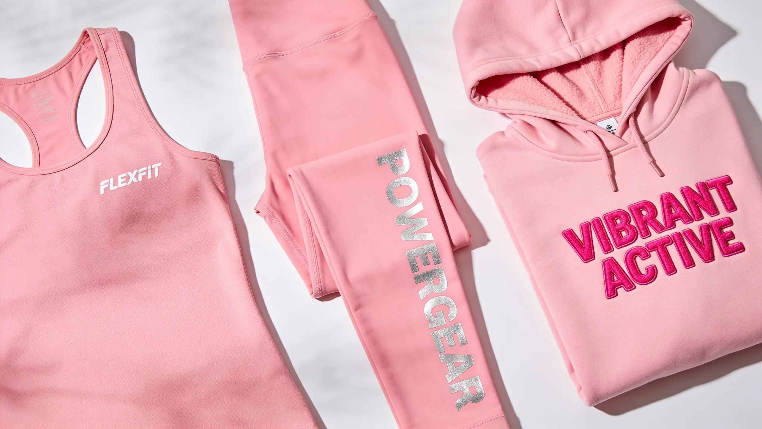 Flat lay of custom pink workout apparel showcasing various branding techniques, highlighting quality and design options