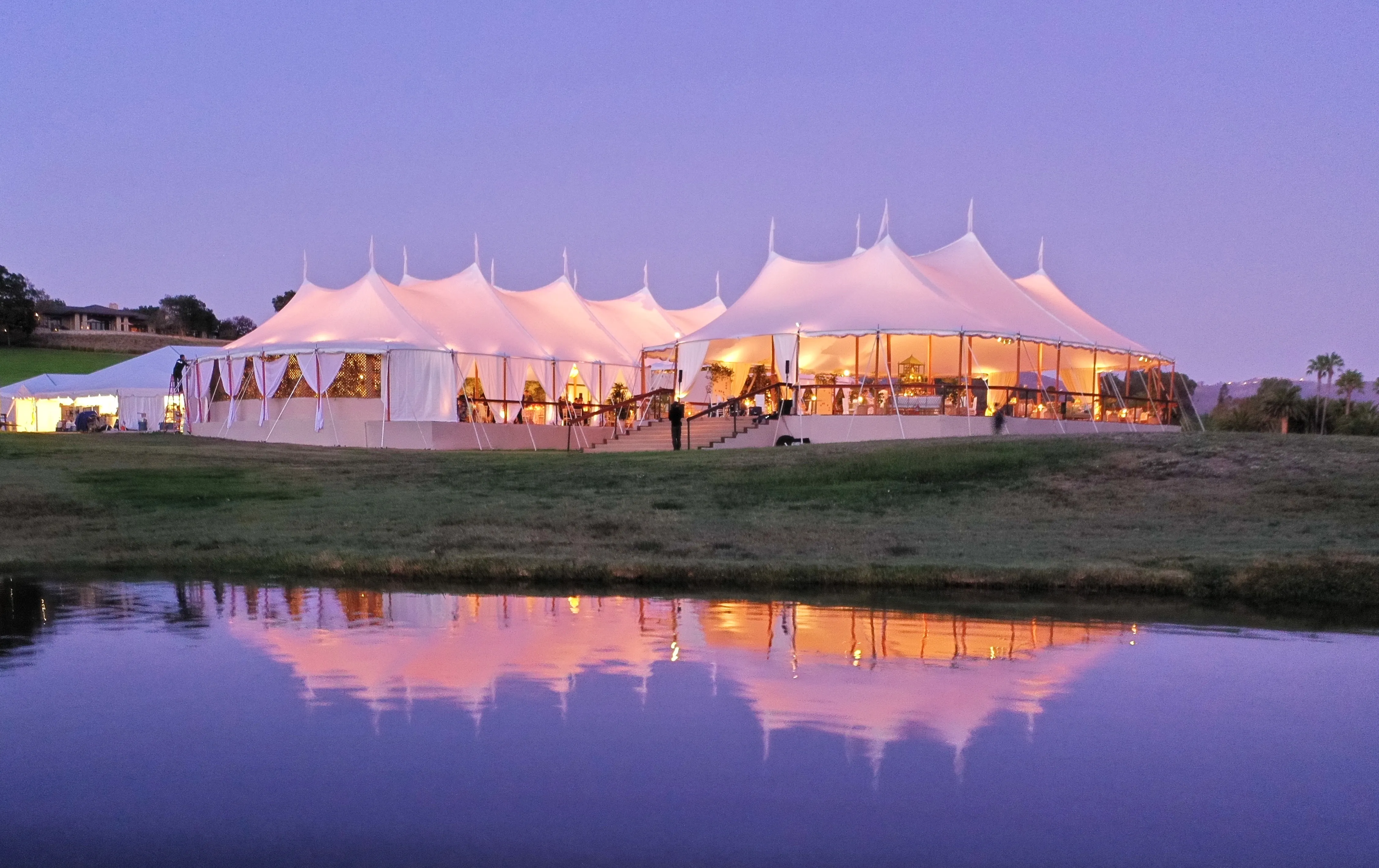 Luxury outdoor party featuring elegant tents, lighting, and décor