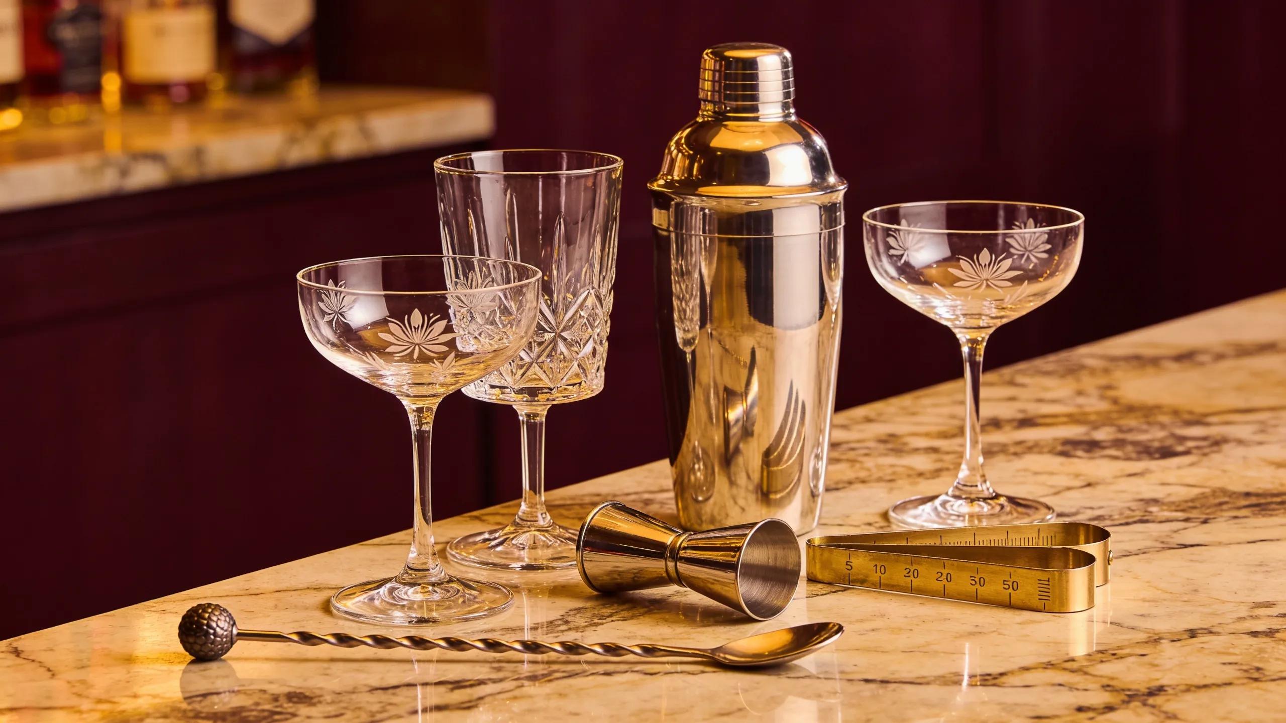 Curated collection of premium barware including elegant glassware and essential tools set in an upscale home bar environment.