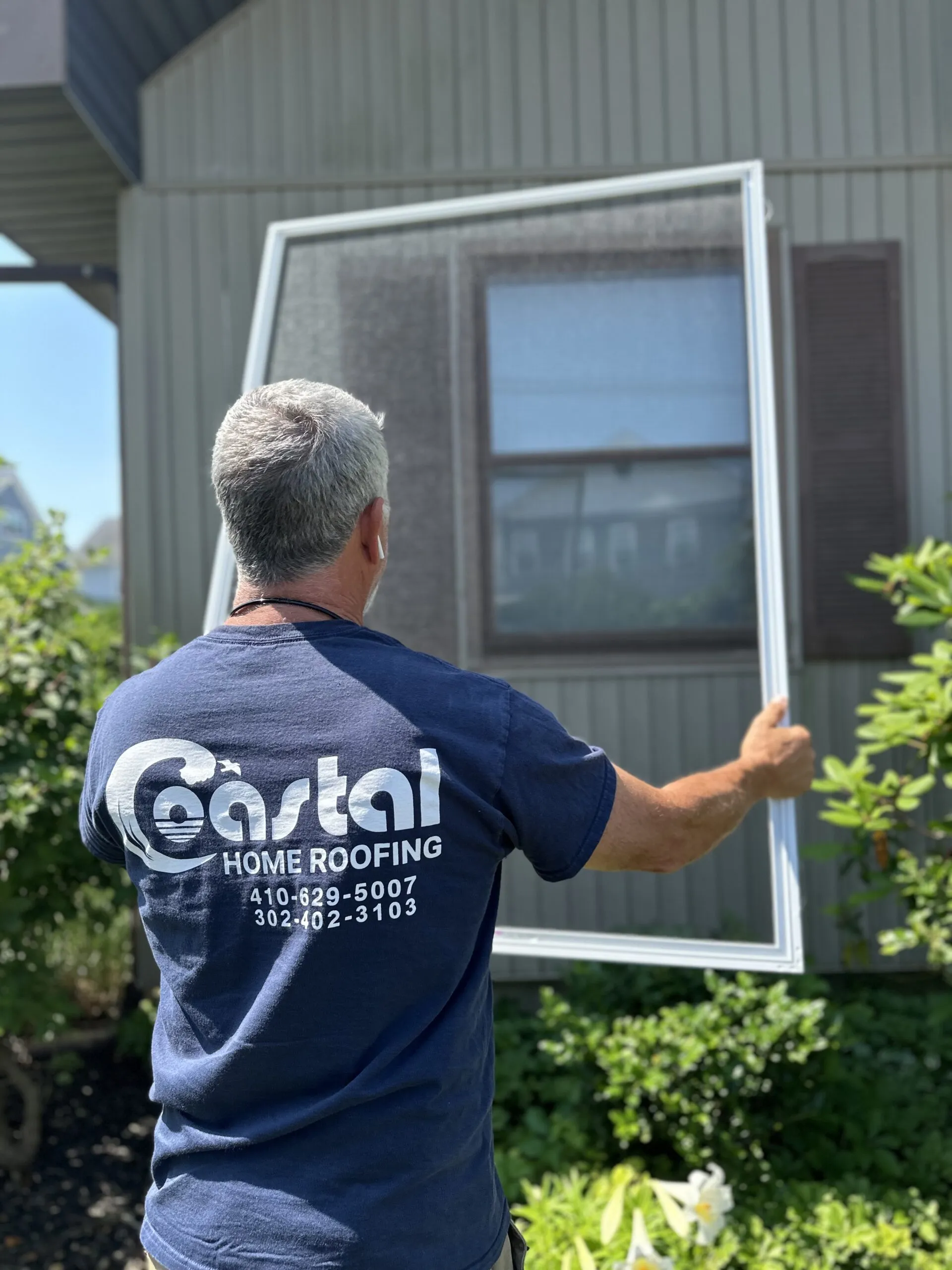 Professional measuring a window during a coastal home replacement project