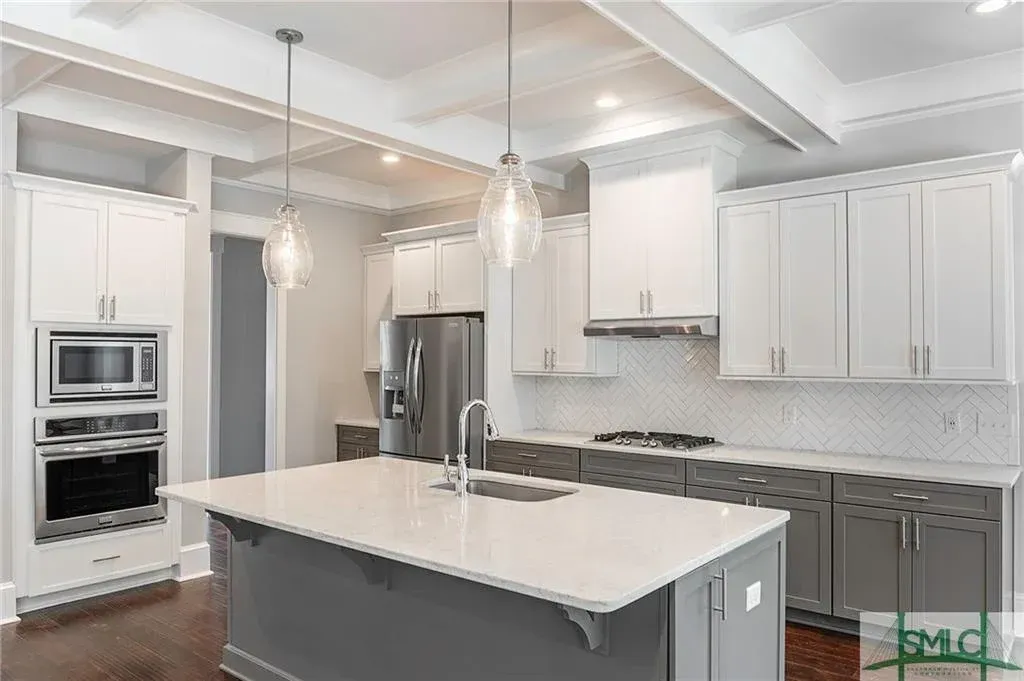 Budget-Friendly Kitchen Cabinet Styles Modern kitchen with gray and white cabinetry, quartz countertop, and pendant lighting