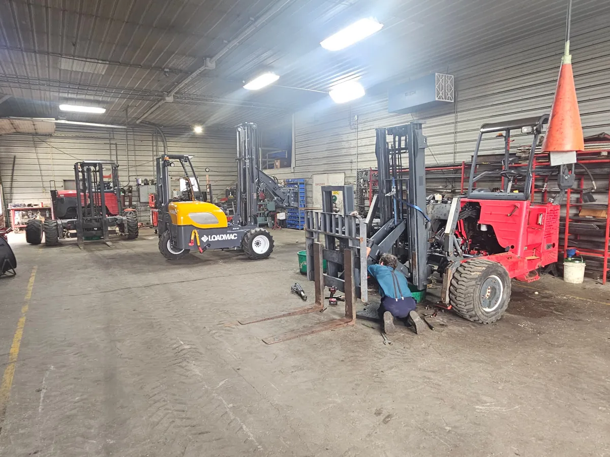 Technician inspecting hydraulic components of a Moffett forklift in a workshop, emphasizing maintenance importance