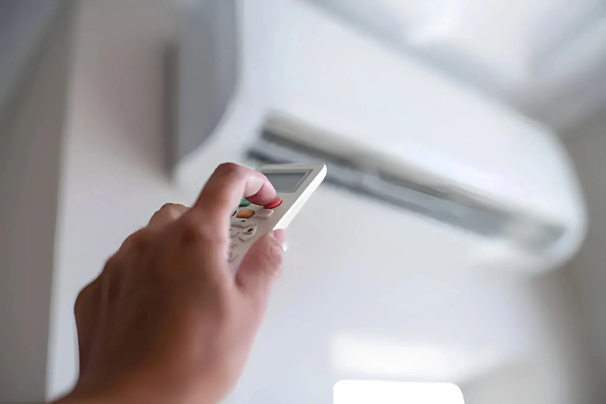 Hands turning an air conditioner on