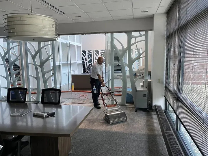 Professional cleaner using advanced upholstery cleaning equipment in modern office setting, emphasizing eco-friendly techniques and efficient stain removal.