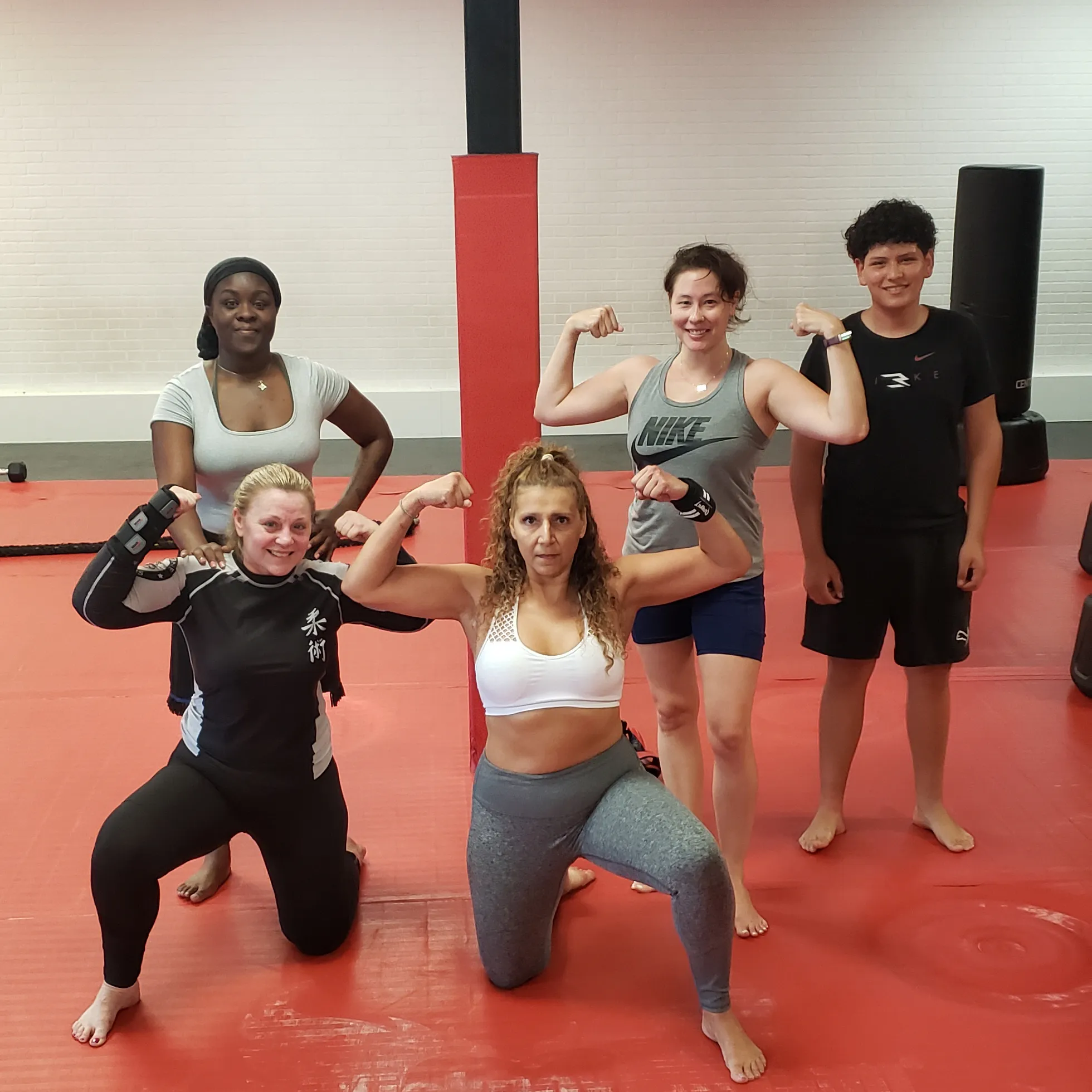 Five individuals flexing muscles in a martial arts training studio Five individuals flexing muscles in a martial arts training studio