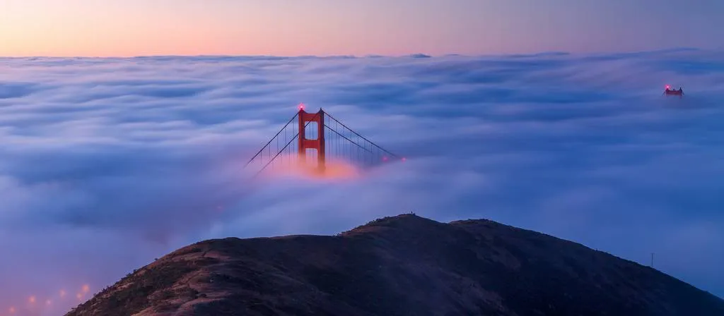 Golden Gate Bridge emerging from the fog at sunset