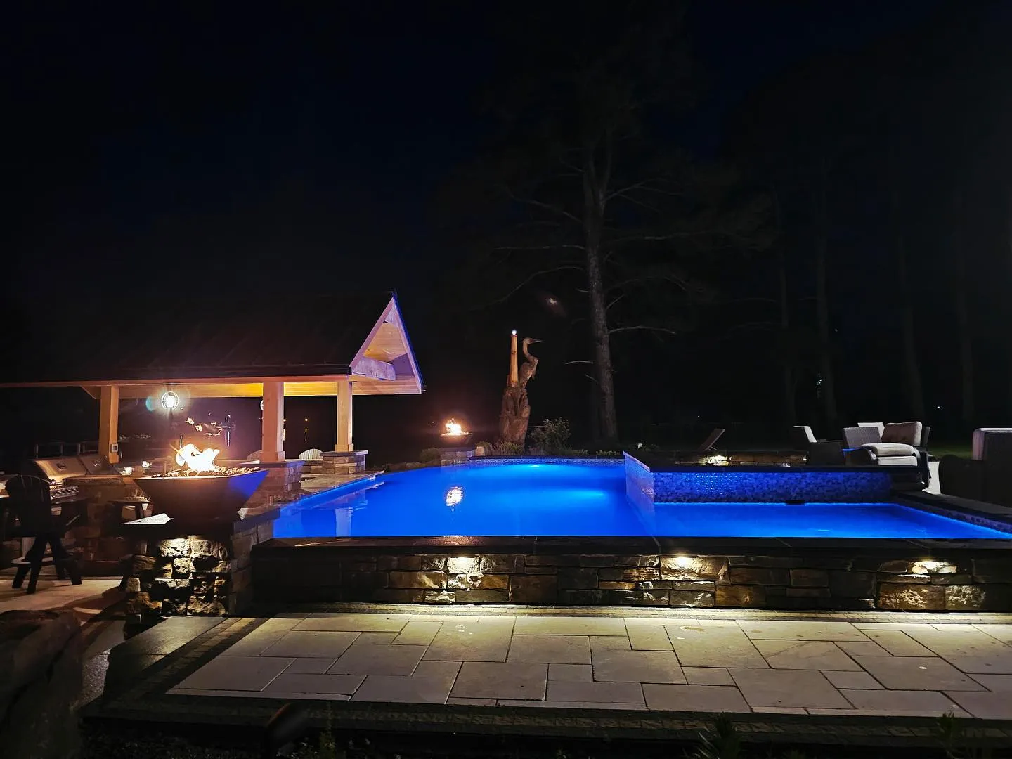 Inground pool with landscape lighting at dusk in a Delaware backyard