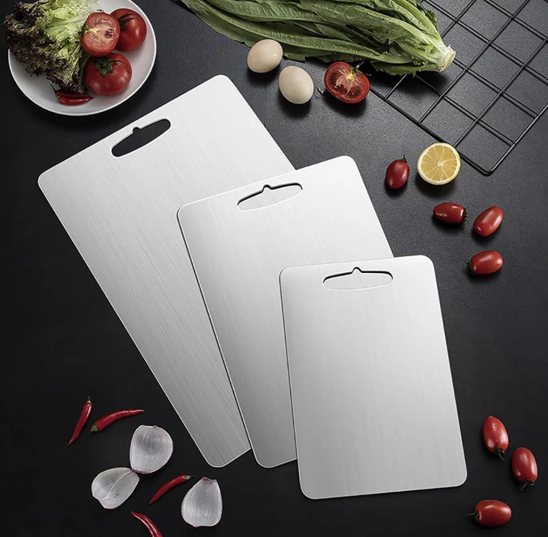 Comparison of titanium, wood, and plastic cutting boards arranged side by side in a kitchen, highlighting their differences