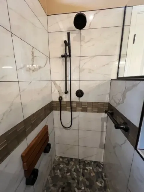 Elegant walk-in shower with glass panels and natural stone tiles, featuring a rainfall showerhead