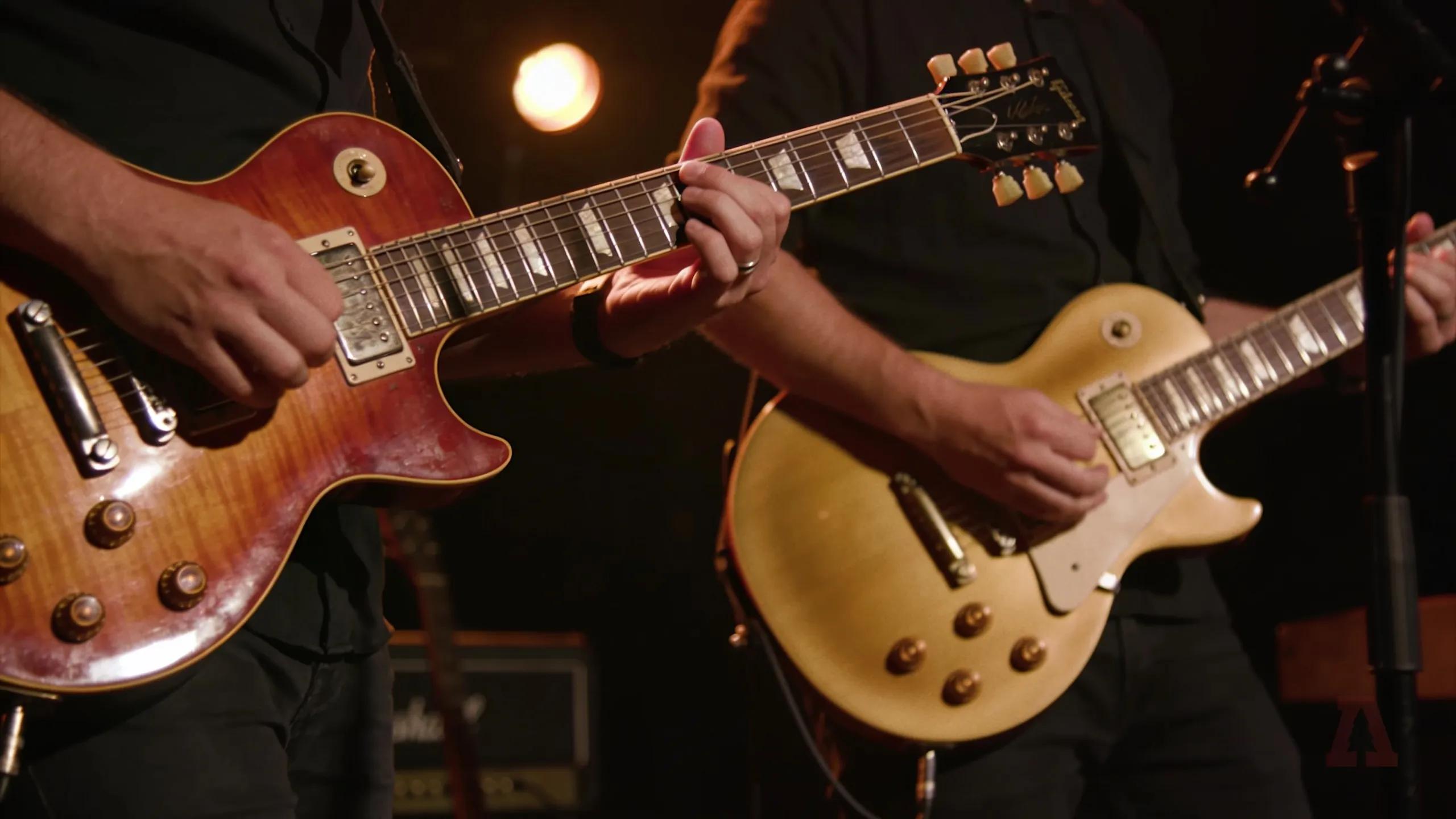Guitarist performing with PRS Custom 24 and Gibson Les Paul on stage, showcasing tonal differences