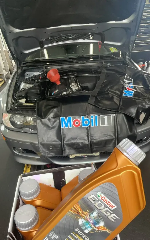 Person pulling dipstick to check engine oil condition in a garage