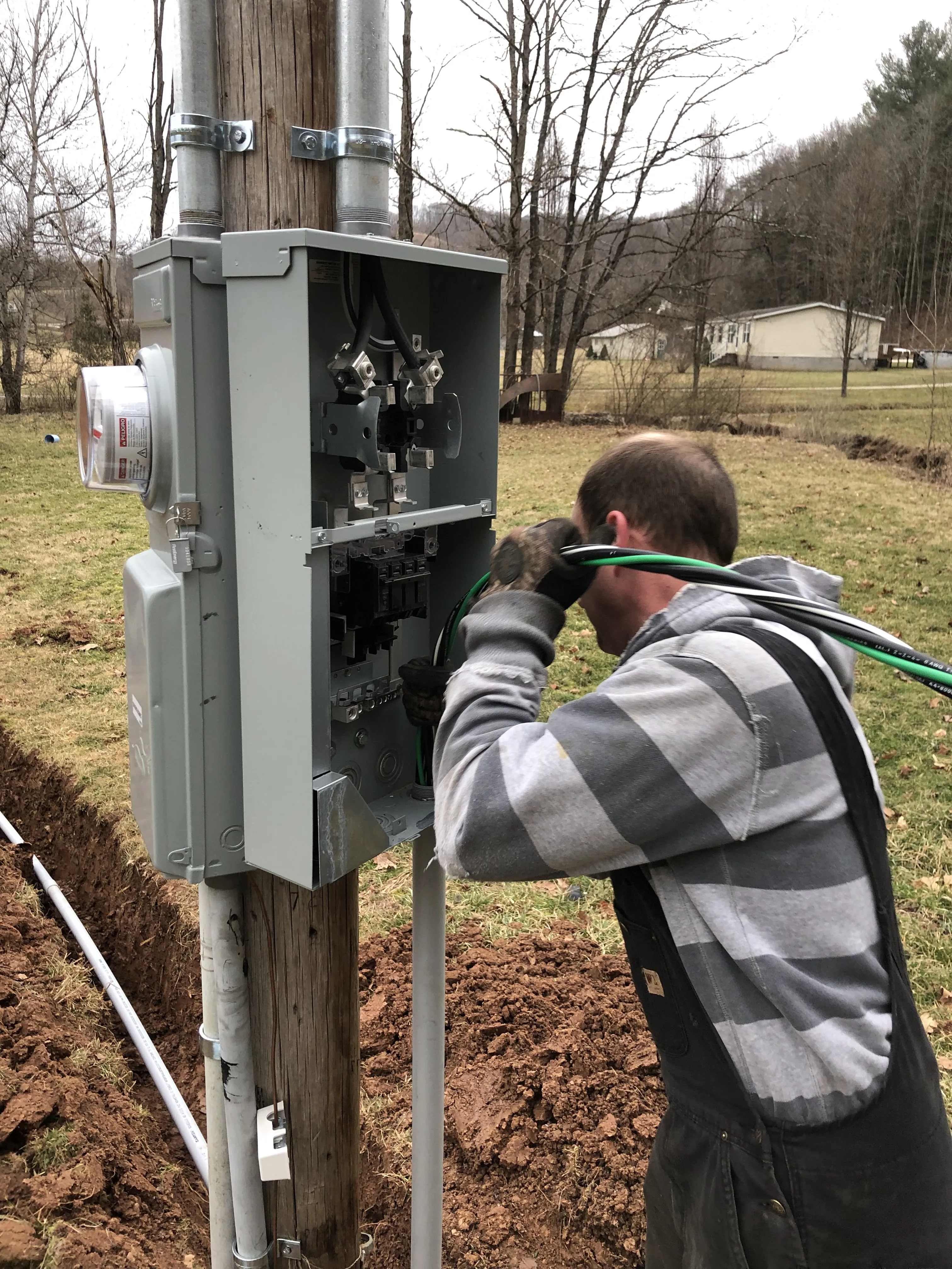 Amped Electric worker installing electrical components on a utility pole at a West Virginia job site