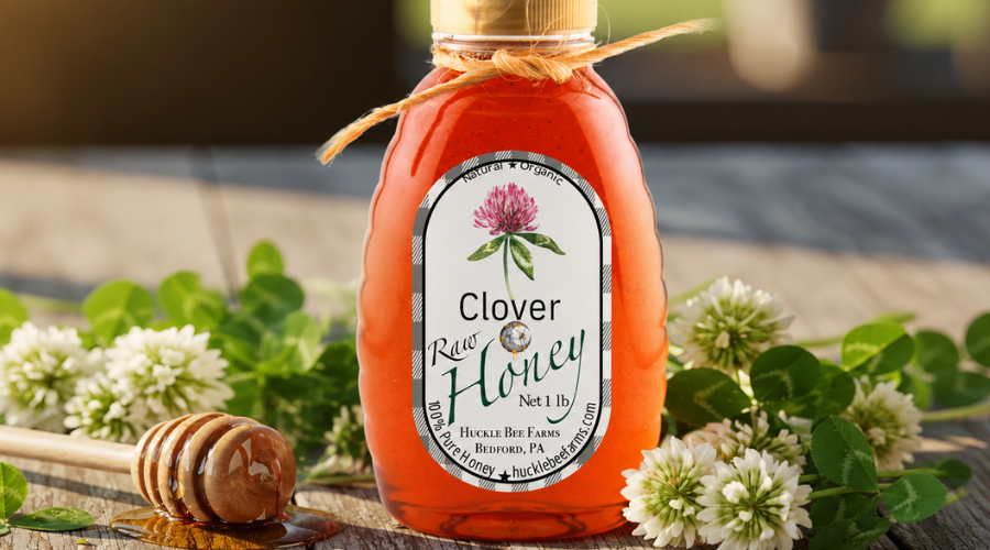 Jar of Huckle Bee Farms Pennsylvania clover honey beside white clover blossoms on a wooden table
