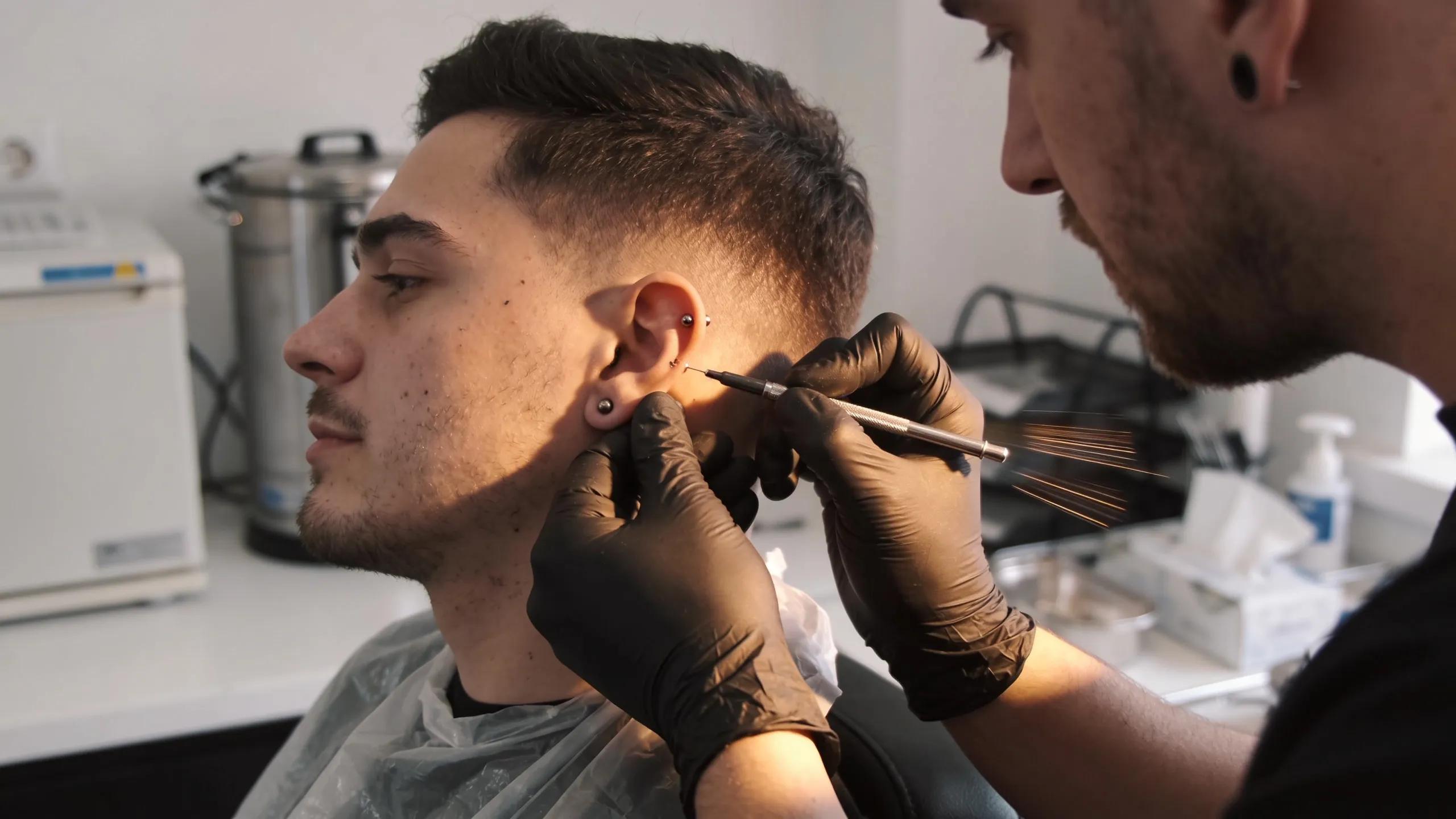 Professional piercing artist performing an ear piercing, showcasing expertise and client trust in the studio.
