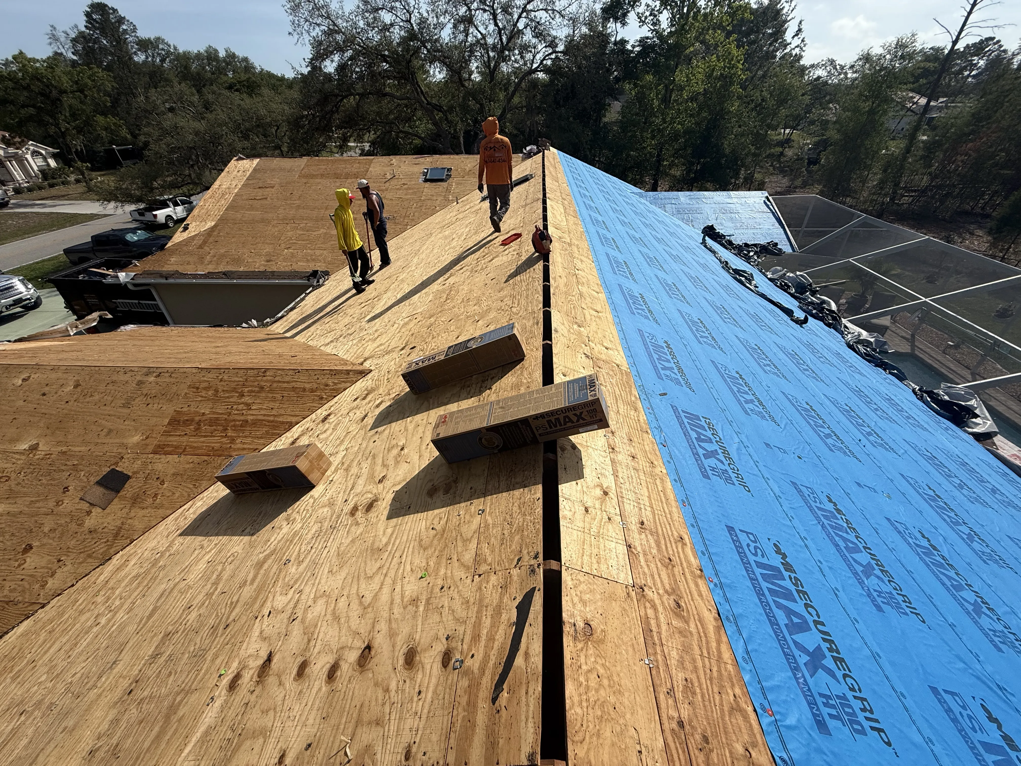 Roofers installing protective underlayment on a home roof to prevent future damage