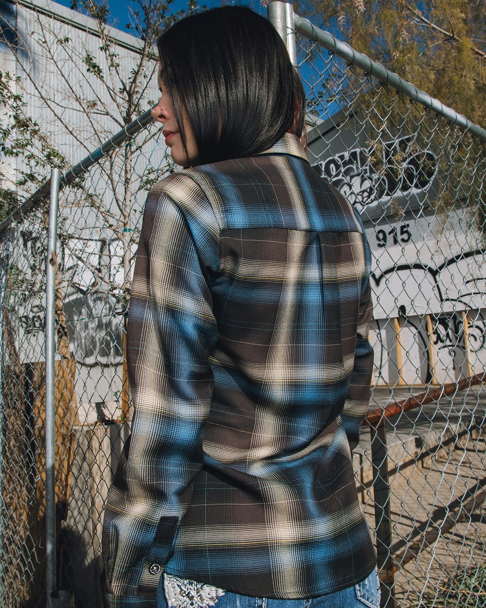 Woman standing in front of metal fence showing the back of Women's Fit for an Autopsy Flannel