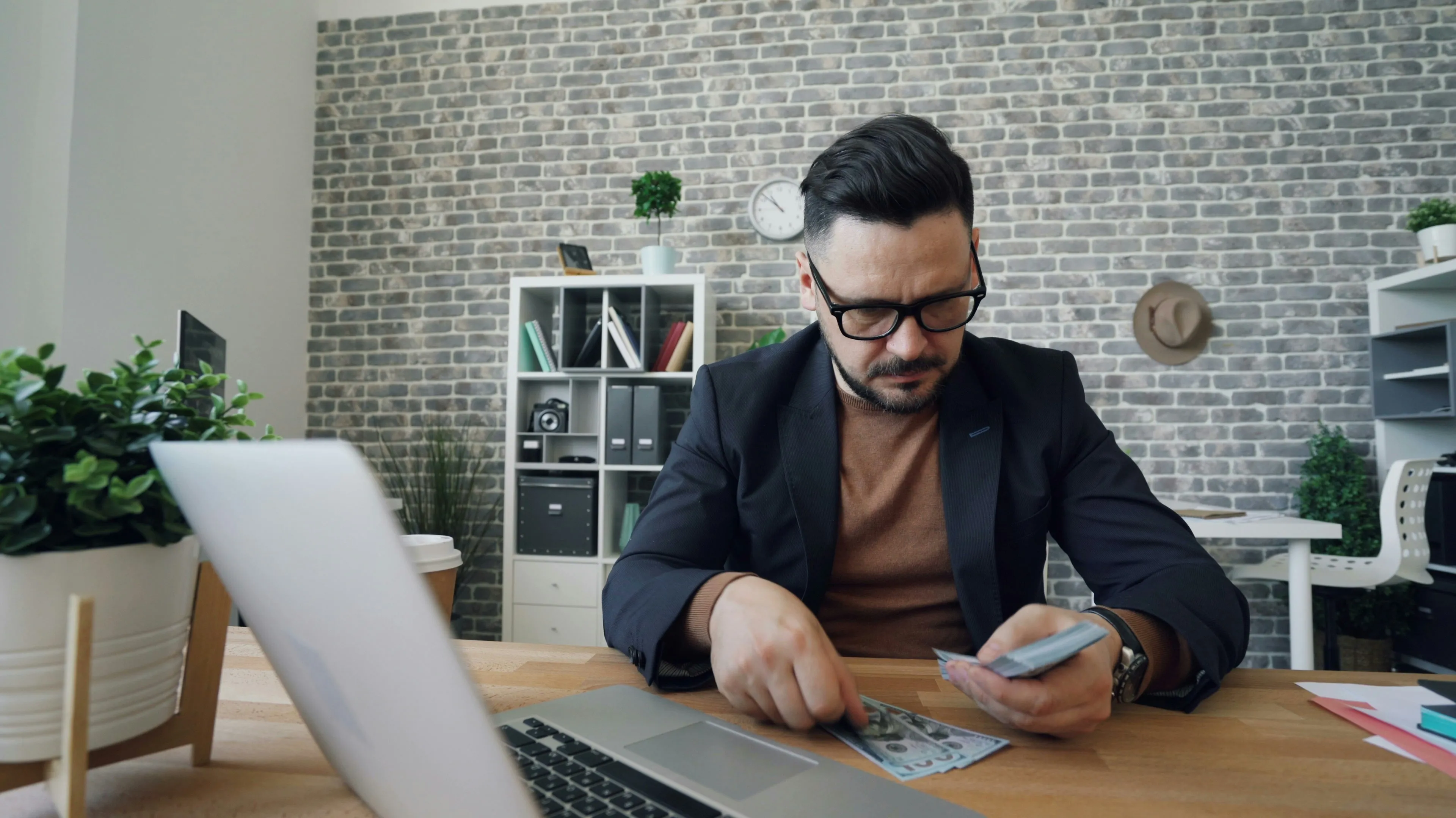 Man reviewing finances and calculating roof repair costs at a desk with laptop and documents