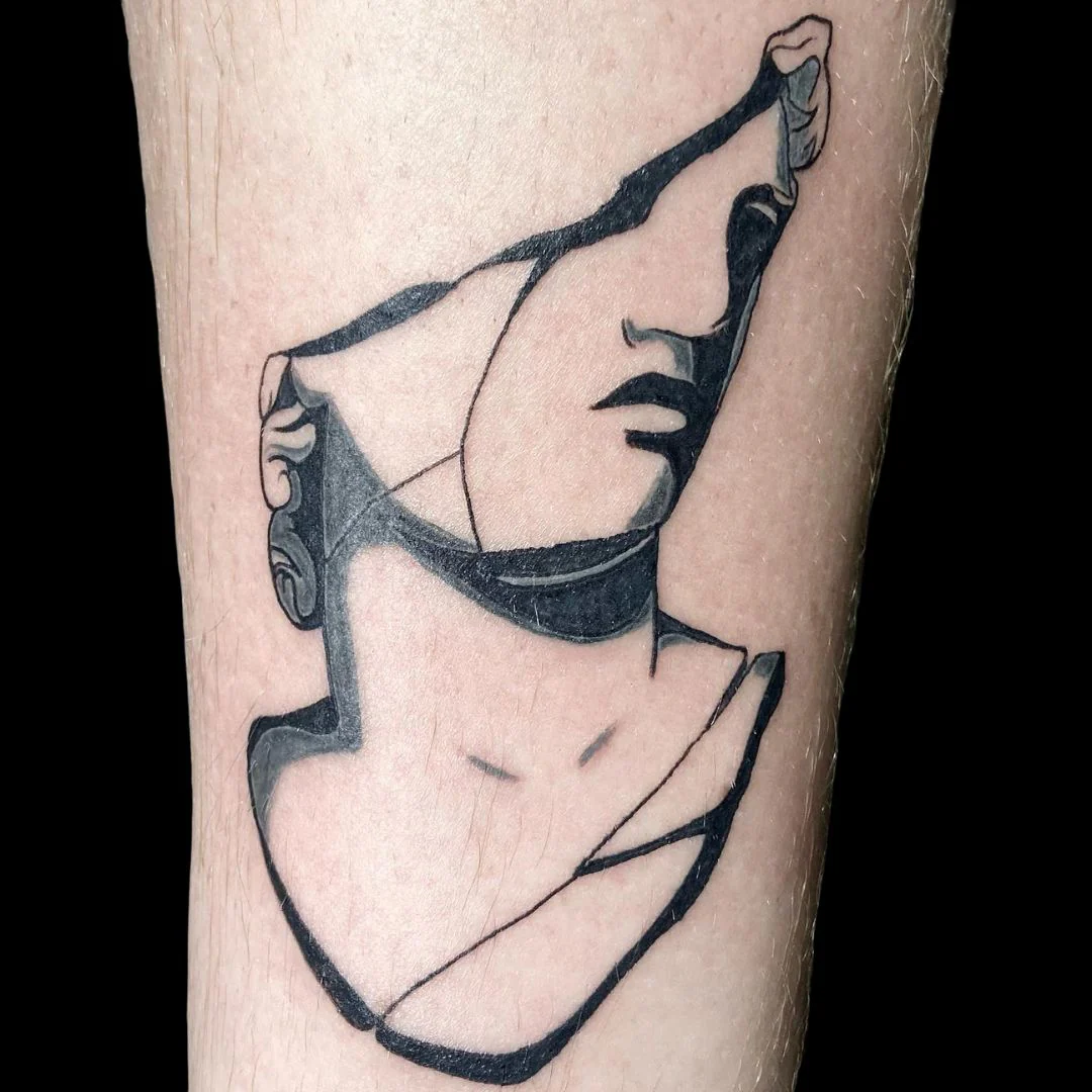A minimalist, bold black-work tattoo on a forearm depicting a fragmented classical bust of a face, using clean lines and solid black shading for a modern, geometric look.