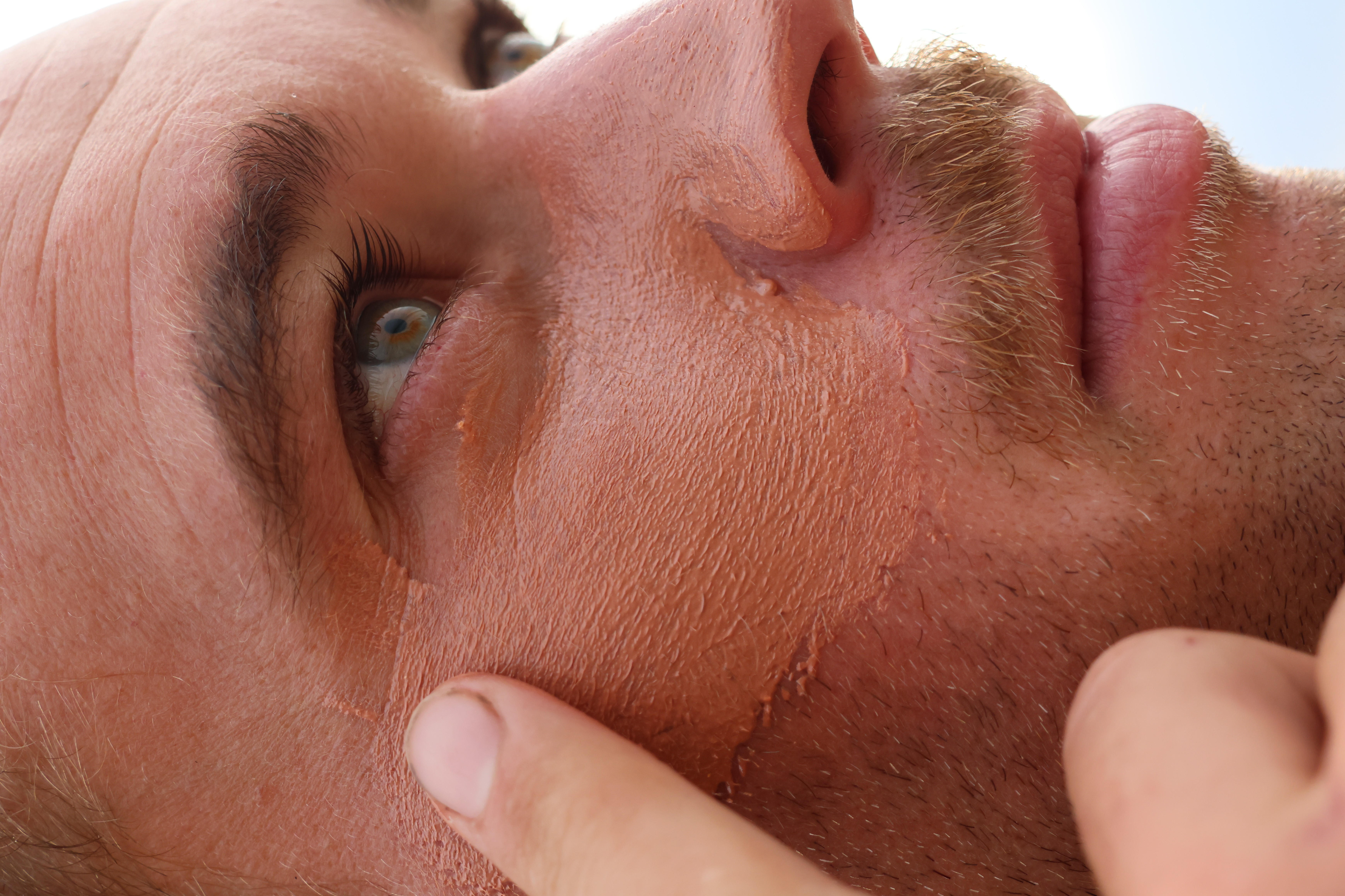 Close-up of a man applying skin treatment on his face