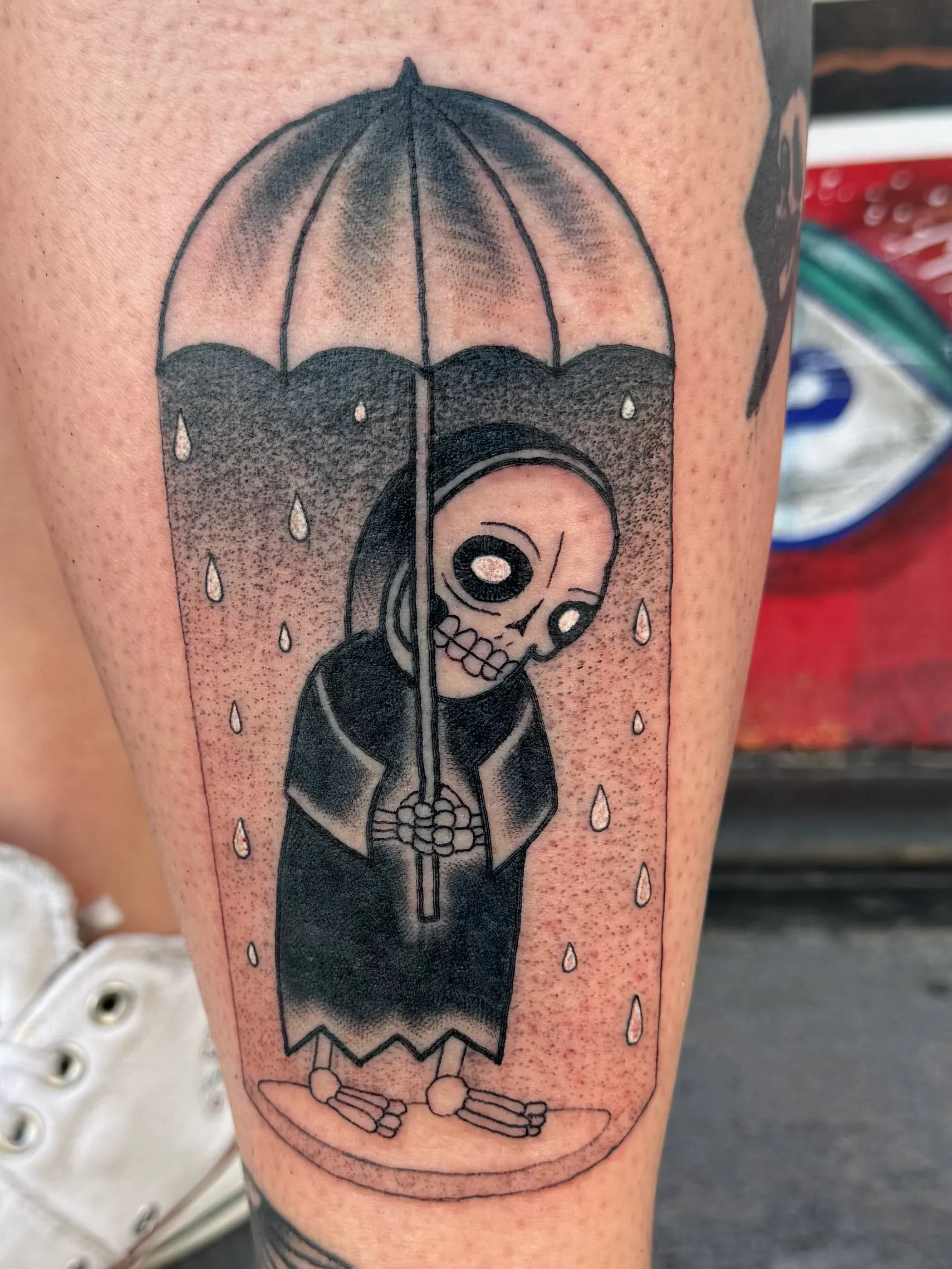 Black and grey illustrative tattoo of a cute grim reaper holding an umbrella in the rain.