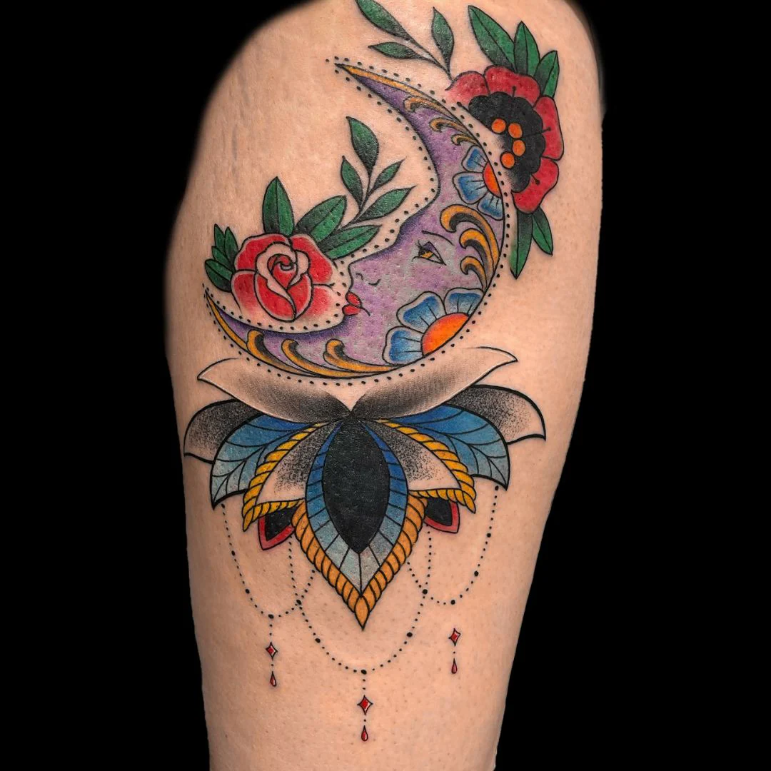 Colorful Neo-Traditional style tattoo on a leg featuring a crescent moon with a detailed woman's face profile in purple and blue tones. The moon is framed by a classic red rose, green leaves, and poppies, resting on top of a sharp, ornamental mandala pattern filled with blue, yellow, and black shading.