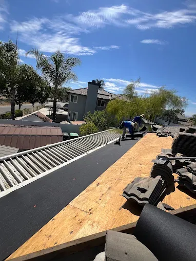 Workers inspecting and preparing the roof deck for metal roof installation