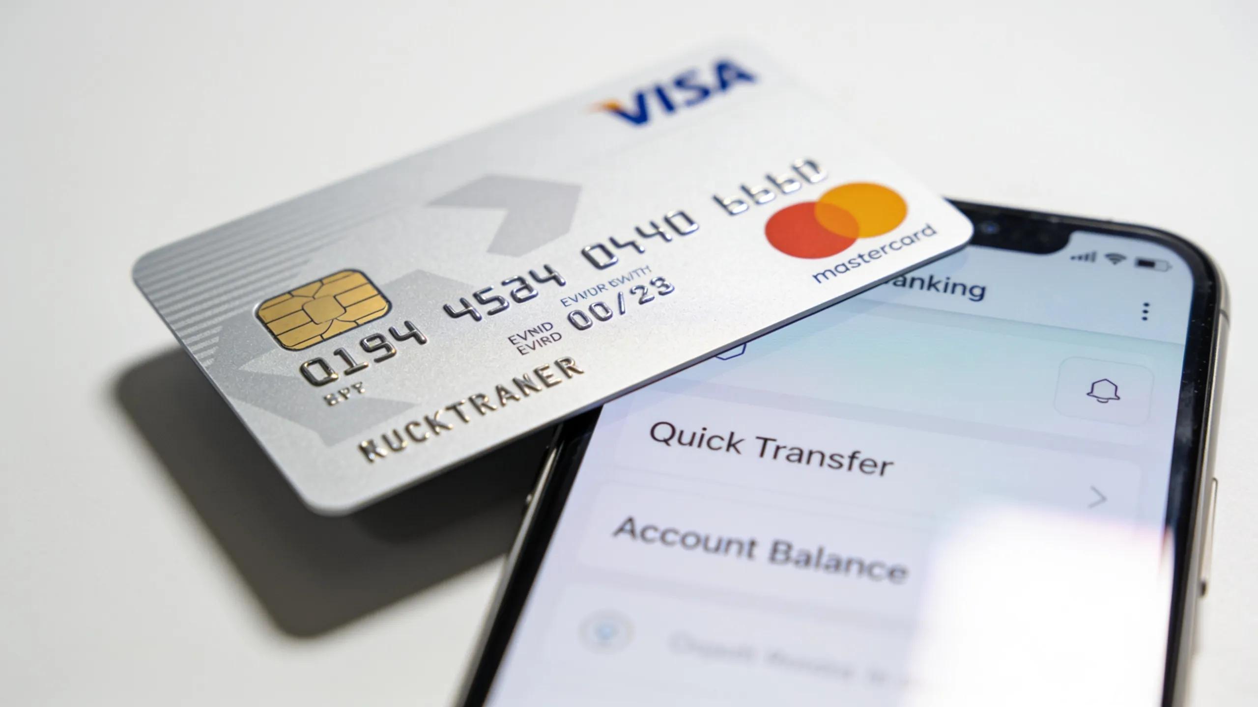 Close-up of a standard debit card and a smartphone banking app for payday loan deposits Close-up of a standard debit card and a smartphone banking app for payday loan deposits