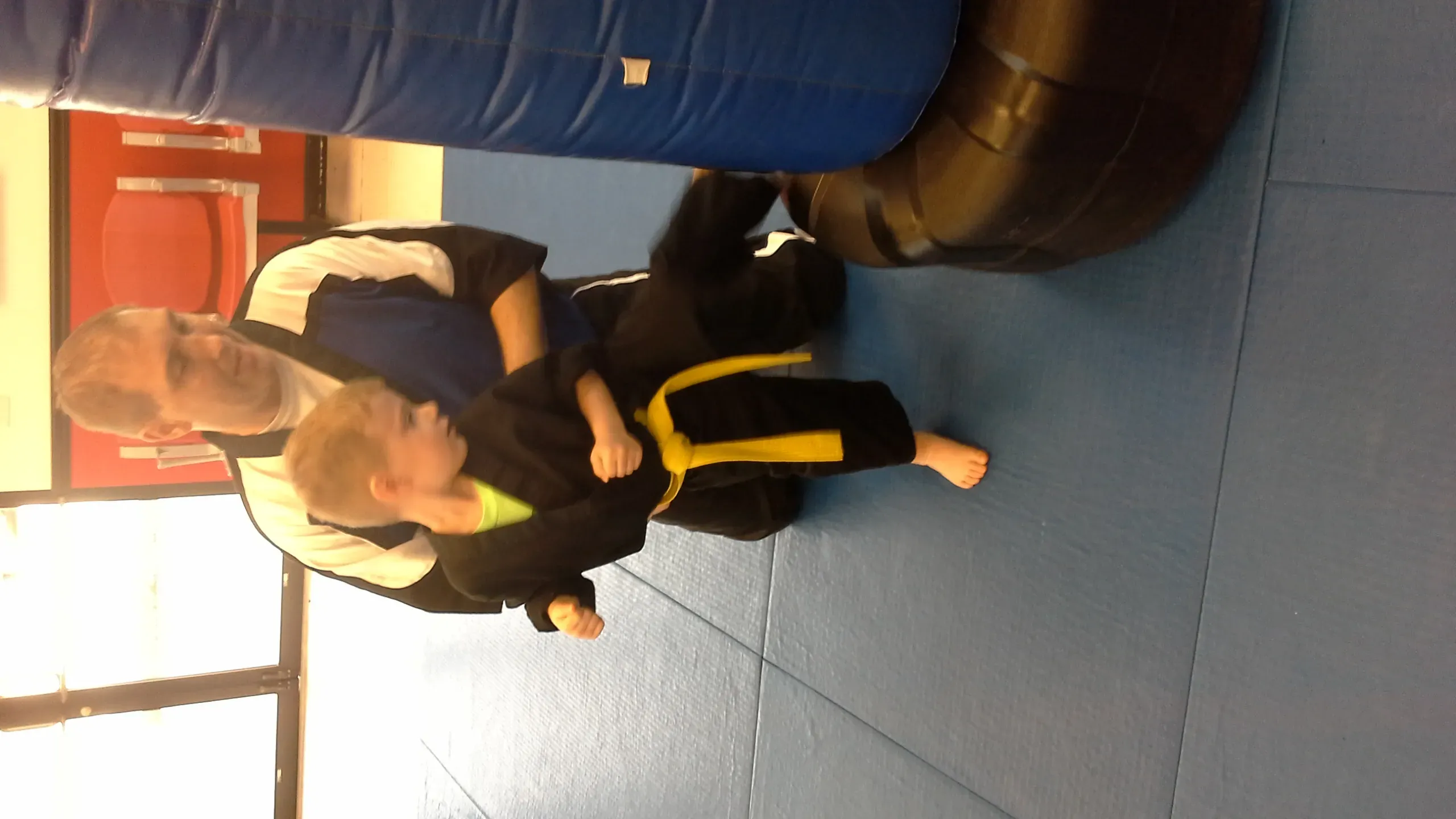 Young children practicing karate skills in a supportive dojo environment, emphasizing early martial arts training