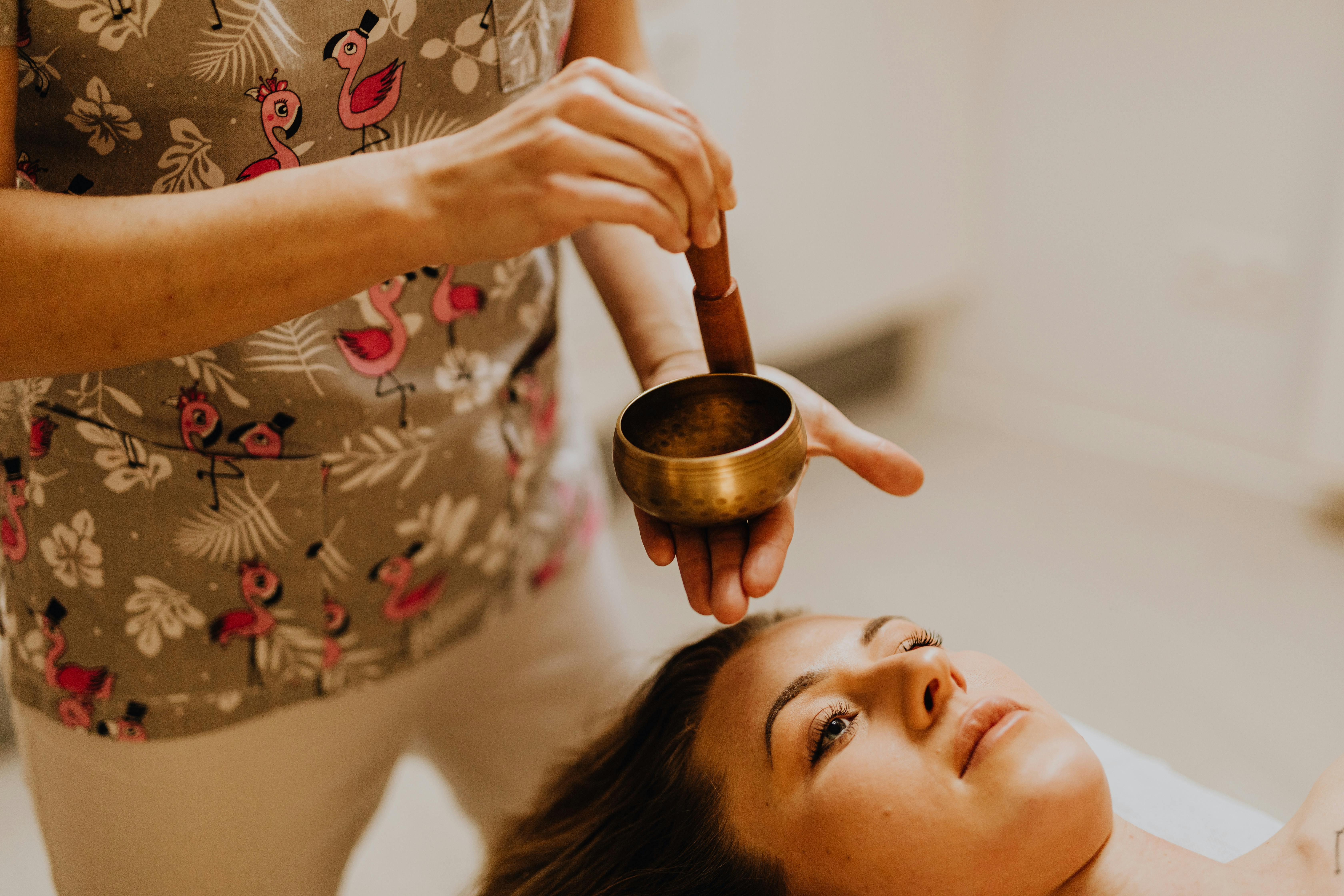 Person meditating with singing bowls, highlighting the benefits of sound therapy