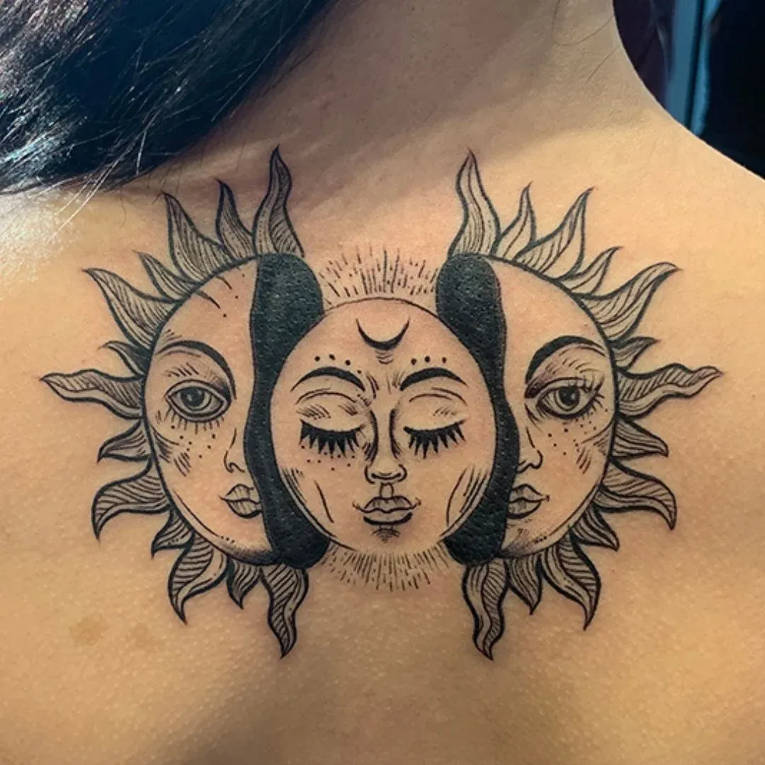 Blackwork upper-back tattoo depicting three celestial sun faces with intricate linework and sunbeams.