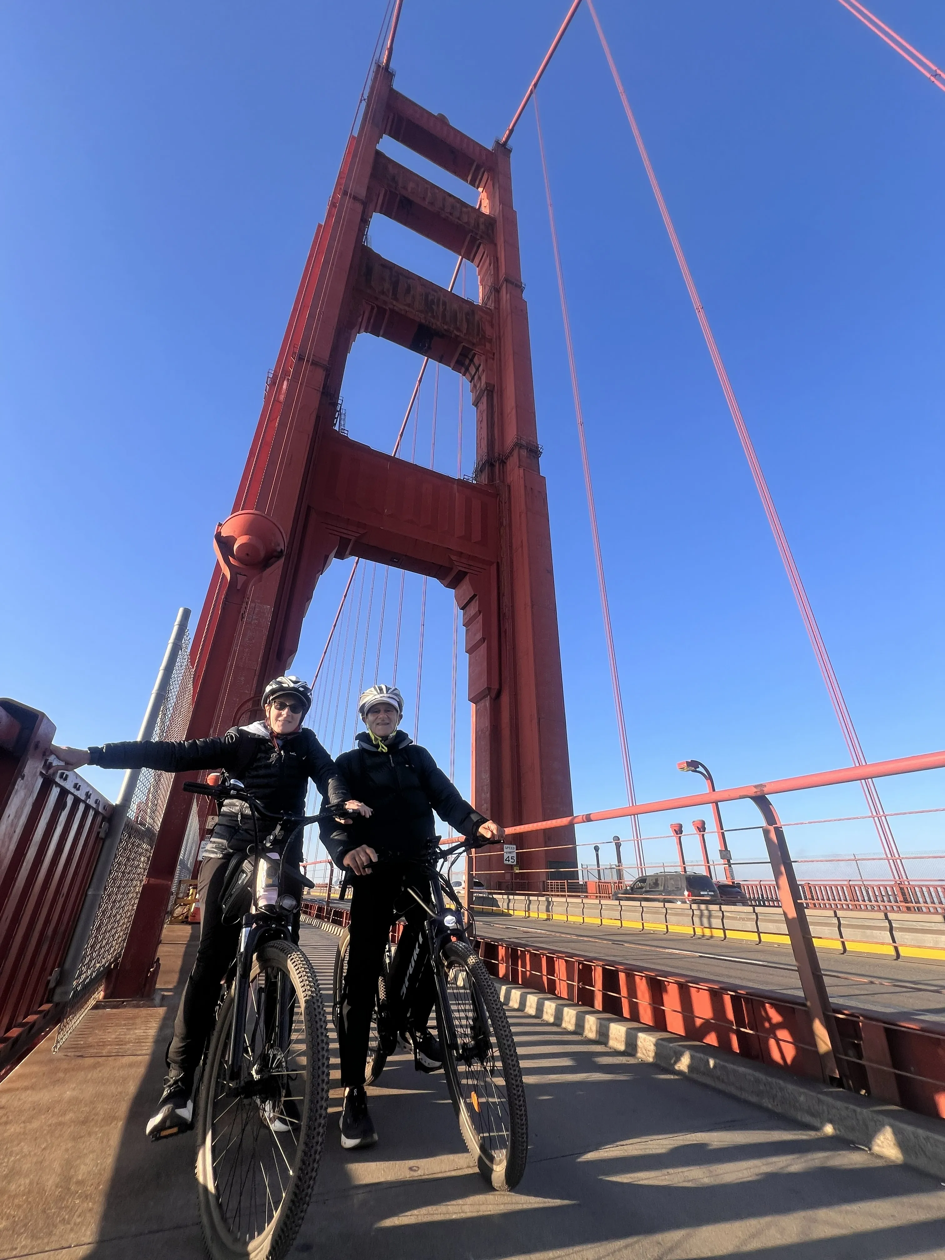 Two smiling cyclists with their bikes on the Golden Gate Bridge