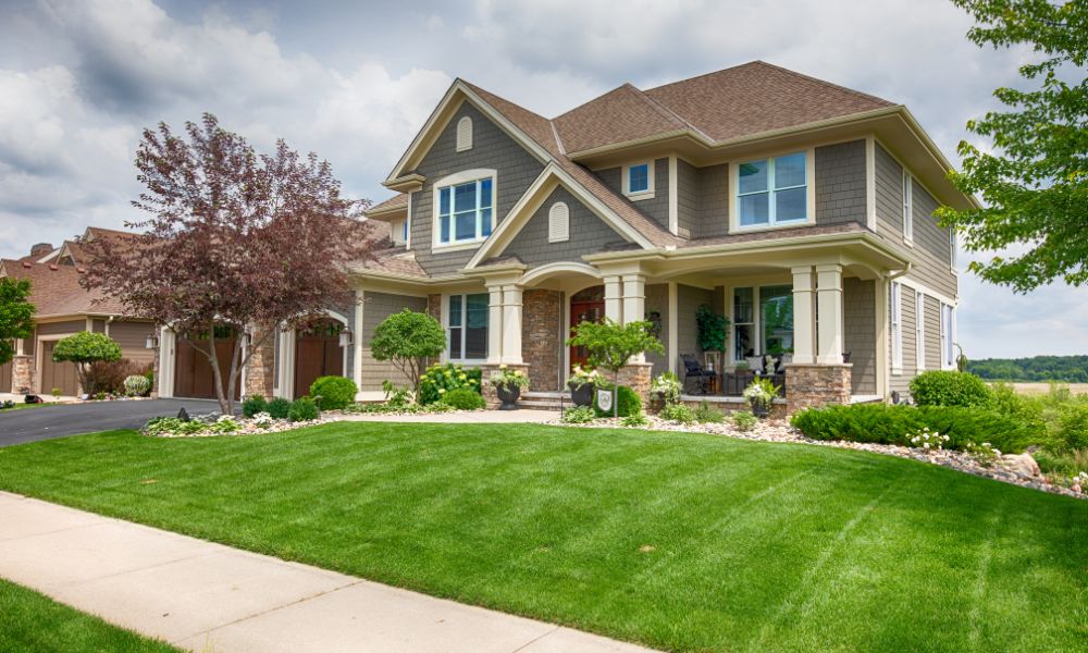 A large luxury craftsman home showcasing high-end features found in Franklin houses for sale, complete with a beautifully manicured green lawn, stone accents, columns, and a welcoming front porch.