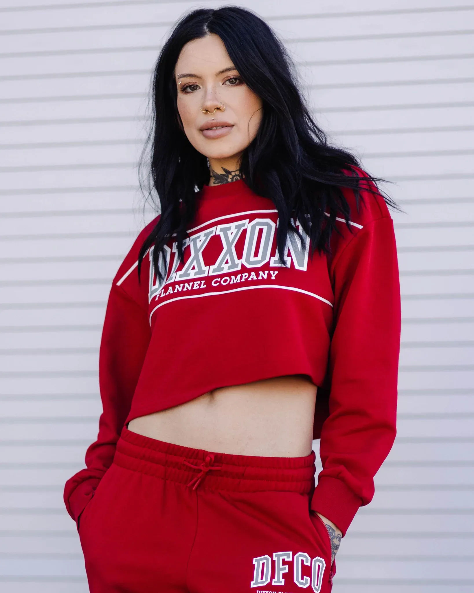 Woman in a red cropped Dixxon Flannel Company crewneck sweatshirt and matching sweatpants.