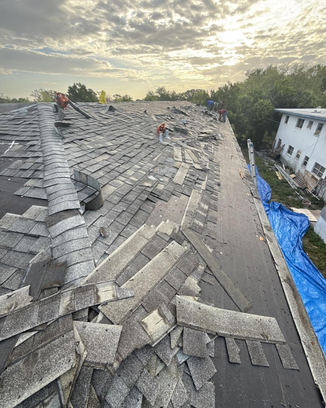 Roofing crew replacing shingles on a residential roof to ensure quality workmanship and durability.