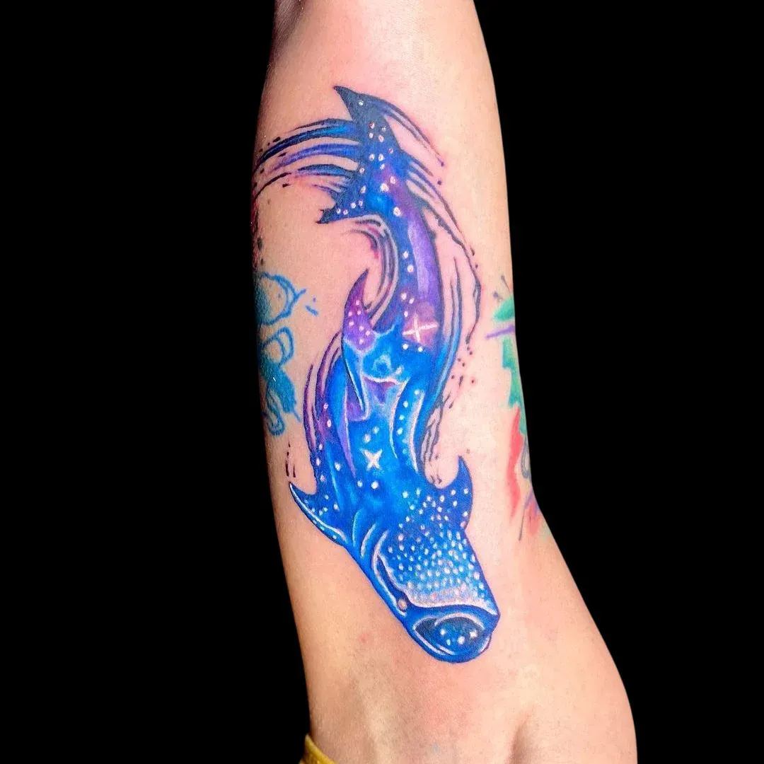 Vibrant galaxy whale shark tattoo in shades of blue and purple by a Club Tattoo artist.
