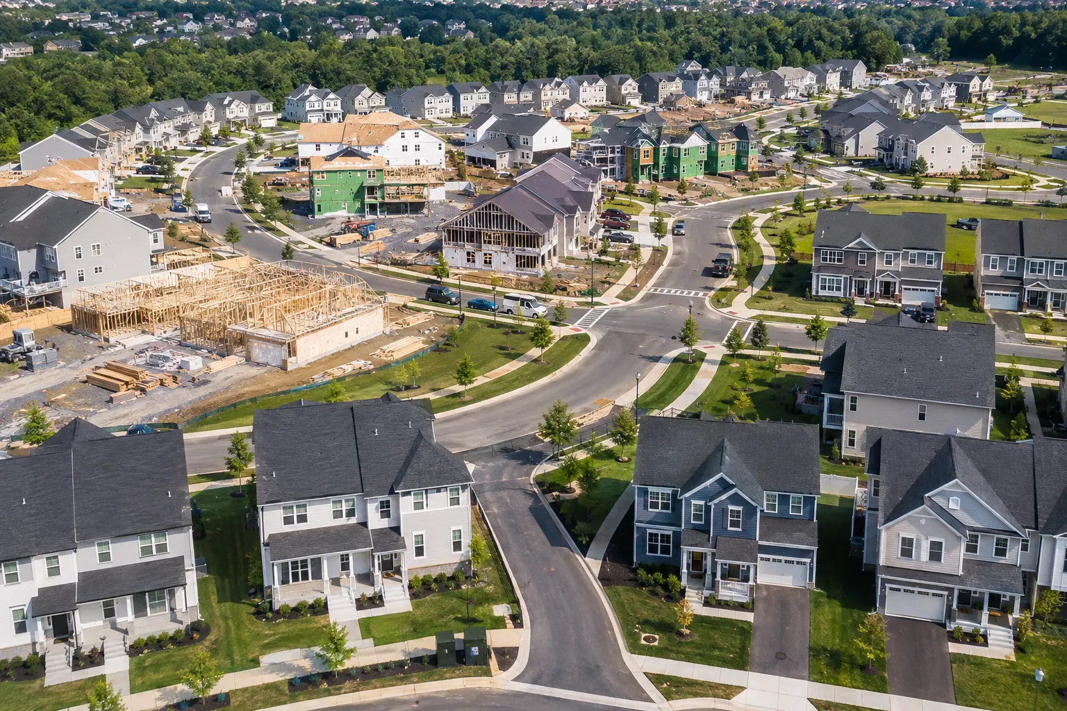A wide aerial view of a new construction community in Northern Virginia showing multiple phases of development, showing finished homes alongside homes under construction. A wide aerial view of a new construction community in Northern Virginia showing multiple phases of development, showing finished homes alongside homes under construction.
