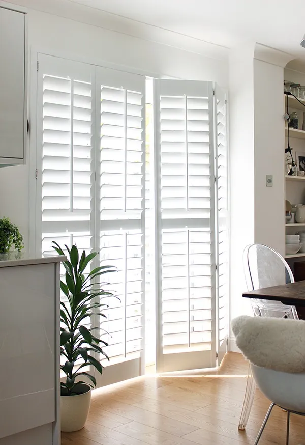 Homeowner cleaning custom plantation shutters to maintain their appearance and longevity